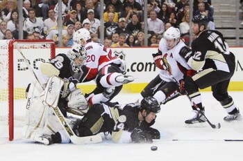 PITTSBURGH - APRIL 11: Goaltender Marc-Andre Fleury #29 of the Pittsburgh Penguins keeps his eyes on the puck as Brooks Orpik #44 of the Penguins slides into Fleury and Antoine Vermette #20 of the Ottawa Senators leaps in front of Fleury during game two o