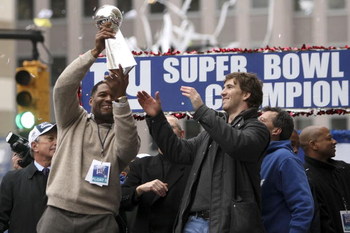 NEW YORK - FEBRUARY 05:  New York Giants defensive end Michael Strahan (L) passes the Vince Lombardi trophy to team mate Eli Manning  during the New York Giants Superbowl XLII victory parade February 5, 2008 in New York City.  (Photo by Chris McGrath/Gett