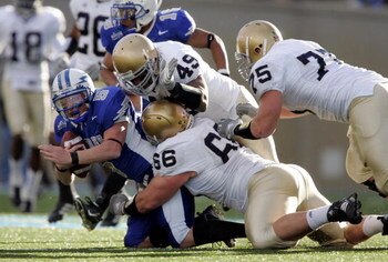 AIR FORCE ACADEMY, CO - NOVEMBER 11:  Defensive linemen Derek Landri #66, Chris Frome #75 and linebacker Tiryan Smith #49 of the Notre Dame Fighting Irish bring down quarterback Shaun Carney #5 of the Air Force Falcons in the second quarter on November 11