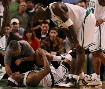 BOSTON - DECEMBER 15:  Paul Pierce #34 of the Boston Celtics is looked after by Ed Lecerte and teammate Kevin Garnett #5 after Pierce injured his knee late in the fourth quarter against the Utah Jazz on December 15, 2008 at TD Banknorth Garden in Boston, 