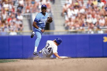 1990:  Frank White #20 of the Kansas City Royals tries to turn a double play as he throws to first base after forcing out the sliding runner at second base during a game in 1990.  (Photo by Otto Greule Jr/Getty Images)