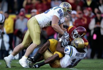 LOS ANGELES, CA - DECEMBER 01:  Jody Adewale #35 of the USC Trojans is tackled by Tom Blake #56 and Chris Horton #14 of the UCLA Bruins during the college football game at the Los Angeles Memorial Coliseum on December 1, 2007 in Los Angeles, California.  
