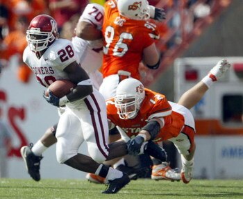 STILLWATER, OK - OCTOBER 30:  Running back Adrian Peterson #28 of the Oklahoma Sooners breaks the tackle of a diving Paul Duren #12 of Oklahoma State at Boone Pickens Stadium on October 30, 2004 in Stillwater, Oklahoma. Oklahoma defeated Oklahoma State 38