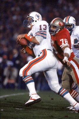 STANFORD, CA - JANUARY 20:  Quarterback Dan Marino #20 of the Miami Dolphins gets sacked by defensive end Dwaine Board #76 of the San Francisco 49ers during Super Bowl XIX at Stanford Stadium on January 20, 1985 in Stanford, California.   The 49ers won 38