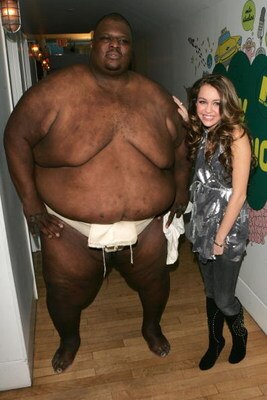 NEW YORK - OCTOBER 23:  (U.S. TABS OUT) Sumo Wrestler Manny Yarbrough poses with Actress Miley Cyrus as she promotes her Walt Disney Records release of the soundtrack from her TV series Hannah Montana while appearing on MTV's Total Request Live October 23