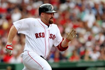 BOSTON - JULY 30:  First baseman Kevin Youkilis #12 of the Boston Red Sox singles against the Oakland A's in the third inning on July 30, 2009 at Fenway Park in Boston, Massachusetts.  (Photo by Elsa/Getty Images)
