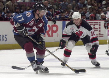 31 May 2001: Ray Bourque #77 of the Colorado Avalanche passes the puck as John Madden #11 of the New Jersey Devils defends during game three of the NHL Stanley Cup Finals at Continental Airlines Arena in East Rutherford, New Jersey. DIGITAL IMAGE Mandat