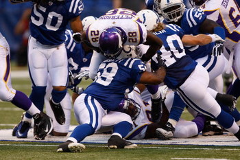 INDIANAPOLIS, IN - AUGUST 14: Running back Adrian Peterson #28 of the Minnesota Vikings is upended as he is tackled by linebacker Michael Taulilli #59 of the Indianapolis Colts at Lucas Oil Stadium on August 14, 2009 in Indianapolis, Indiana. (Photo by S