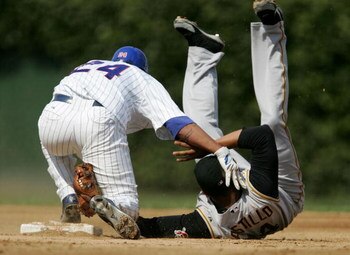 CHICAGO - SEPTEMBER 07:   Jose Castillo #14 of the Pittsburgh Pirates ends up on his back after trying to tag Henry Blanco #24 of the Chicago Cubs after Blanco hits a double in the 2nd inning on September 07, 2006 at Wrigley Field in Chicago, Illinois.   