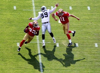 SAN FRANCISCO - AUGUST 22:  Alex Smith #11 of the San Francisco 49ers blocks against Greg Ellis #99 of the Oakland Raiders as Arnaz Battle #83 runs on a reverse during a preseason game on August 22, 2009 at Candlestick Park in San Francisco, California.  