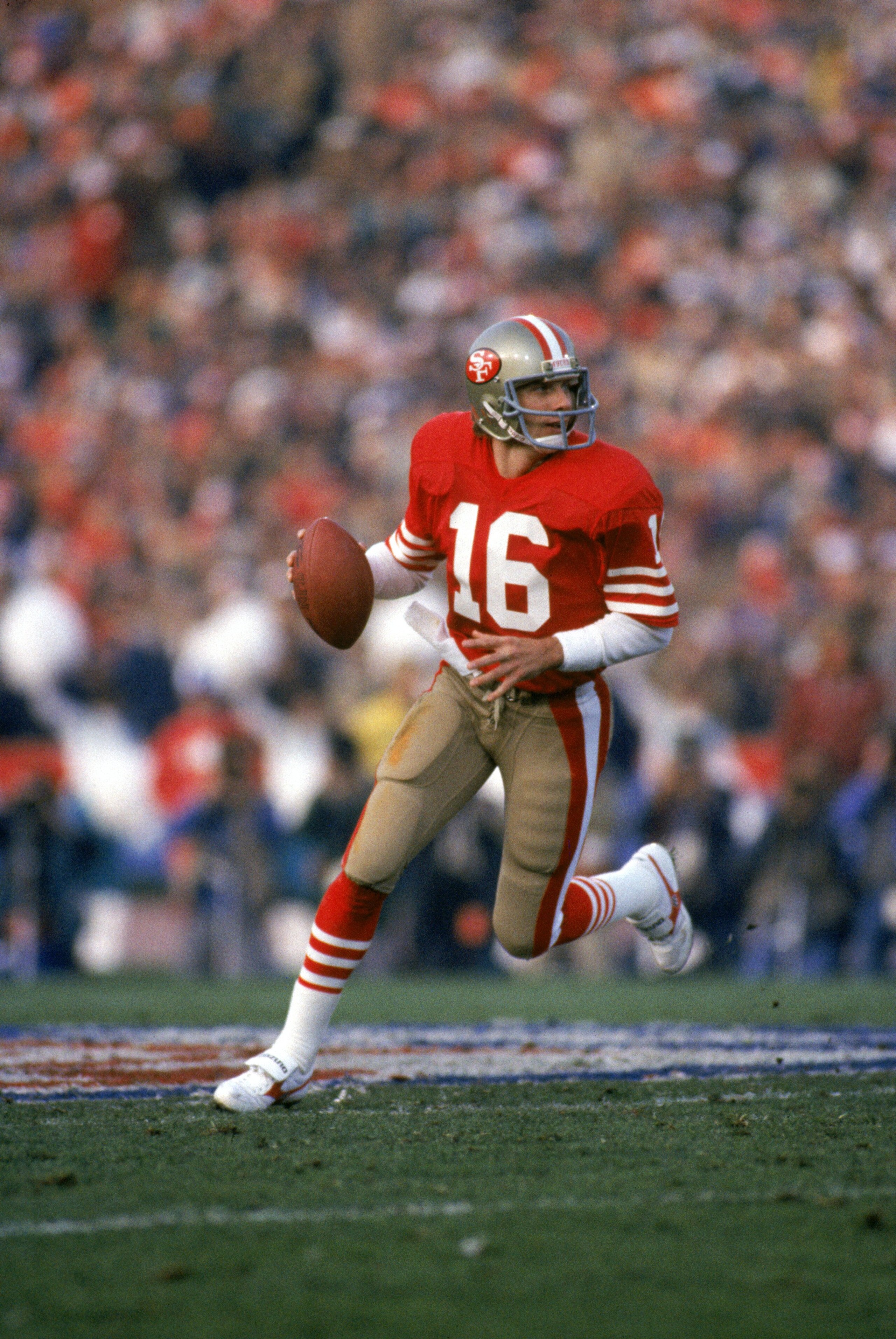 STANFORD, CA - JANUARY 20:  Quarterback Joe Montana #16 of the San Francisco 49ers runs with the ball as he looks downfield for a receiver in Super Bowl XIX against the Miami Dolphins at Stanford Stadium on January 20, 1985 in Stanford, California. The 49