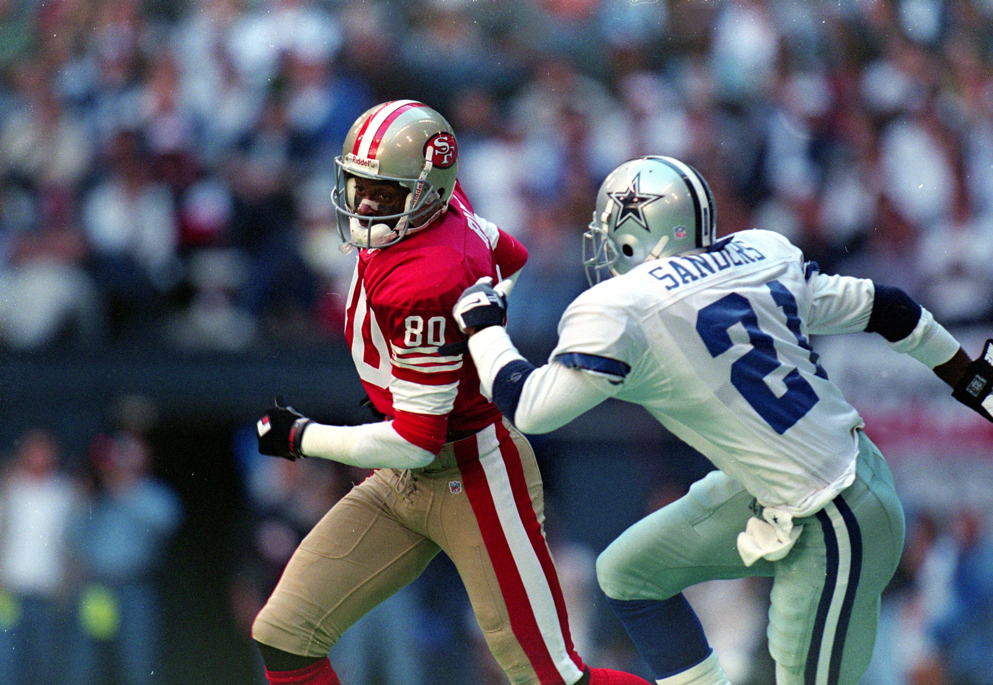 12 Nov 1995: Jerry Rice #80 of the San Francisco 49ers runs with the ball as Deion Sanders #21 of the Dallas Cowboys runs after him during the game at the Texas Stadium in Irving, Texas. The 49ers defeated the Cowboys 38-20.