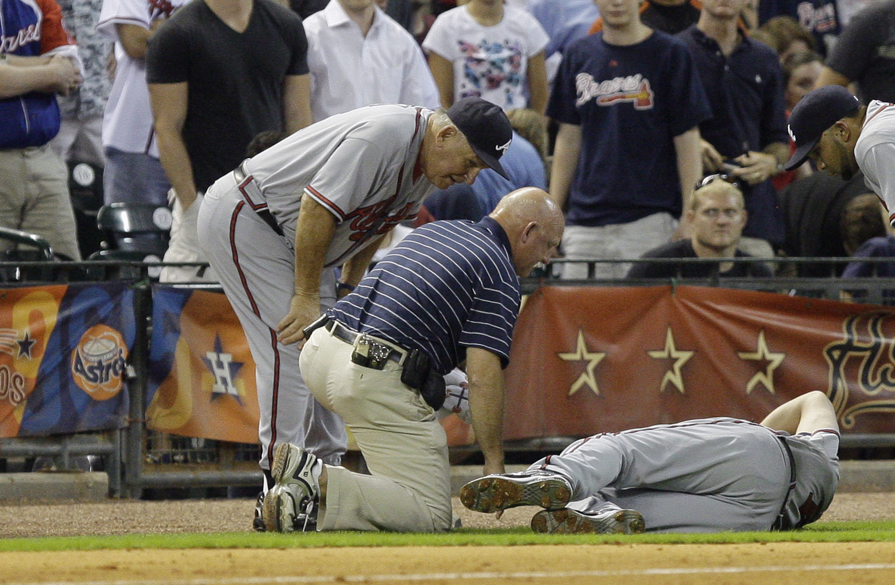 HOUSTON - AUGUST 10:  Third baseman Chipper Jones #10 of the Atlanta Braves is tended to by the trainer and manager Bobby Cox after coming down awkardly behind the base at Minute Maid Park on August 10, 2010 in Houston, Texas. Jones left the game after in