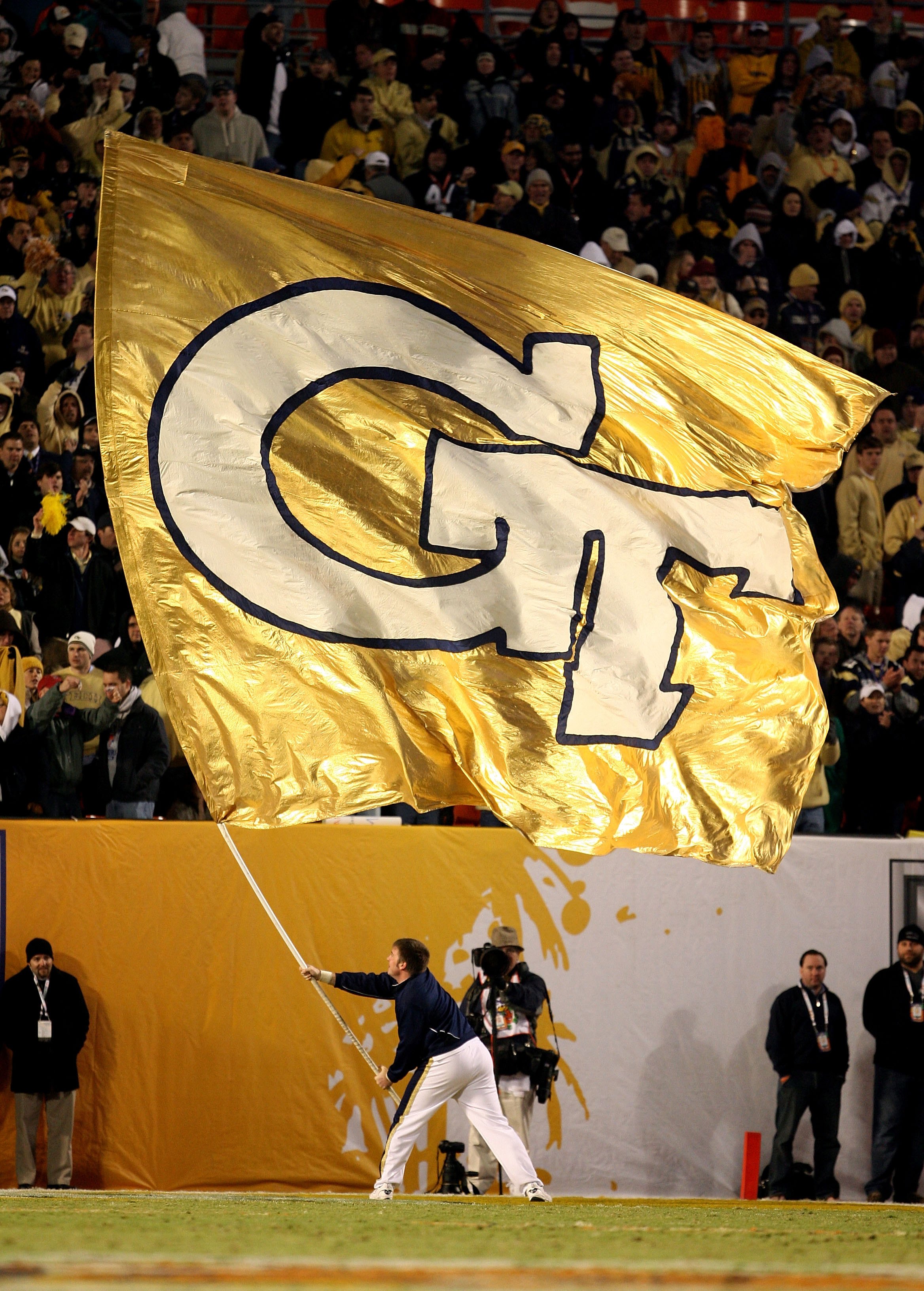 MIAMI GARDENS, FL - JANUARY 05: A male cheerleader from the Georgia Tech Yellow Jackets waves a giant flag in support of his team against the Iowa Hawkeyes during the FedEx Orange Bowl at Land Shark Stadium on January 5, 2010 in Miami Gardens, Florida.