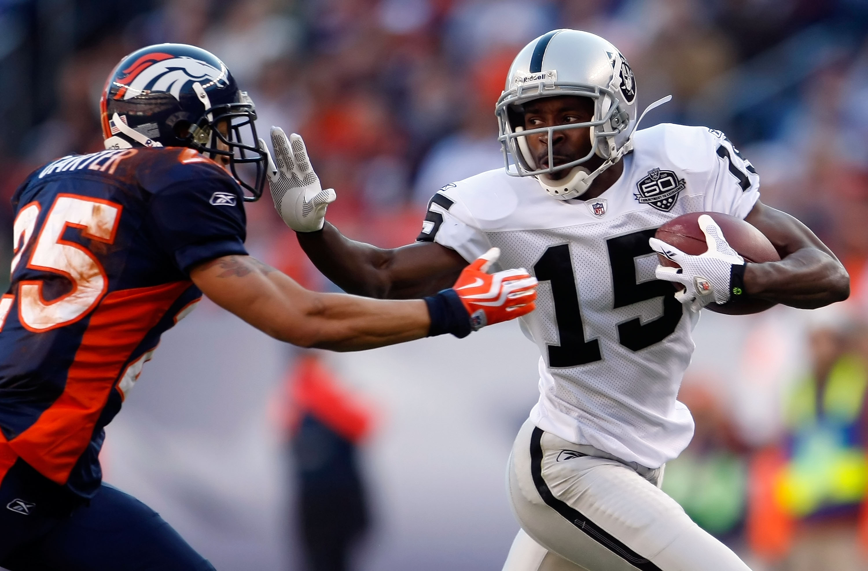 DENVER - DECEMBER 20: Johnnie Lee Higgins #15 of the Oakland Raiders stiff arms Tony Carter #25 of the Denver Broncos in the first half at Invesco Field at Mile High on December 20, 2009 in Denver, Colorado. The Raiders defeated the Broncos 20-19. (Phot