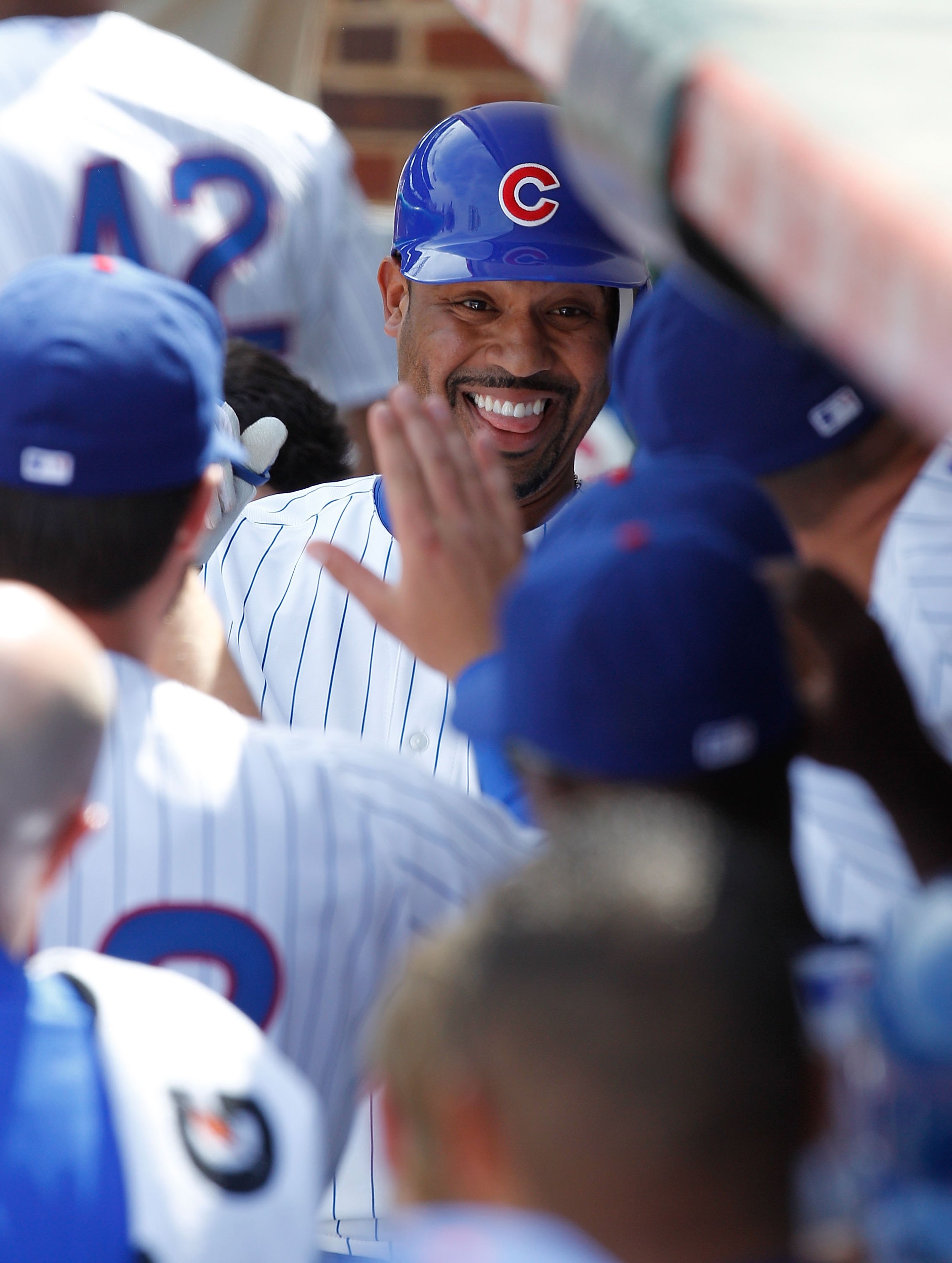 CHICAGO - APRIL 15: Derrek Lee of the Chicago Cubs, wearing a number 42 jersey in honor of Jackie Robinson, is greeted by teammates in the dugout after hitting a home run in the 1st inning against the Milwaukee Brewers at Wrigley Field on April 15, 2010 i