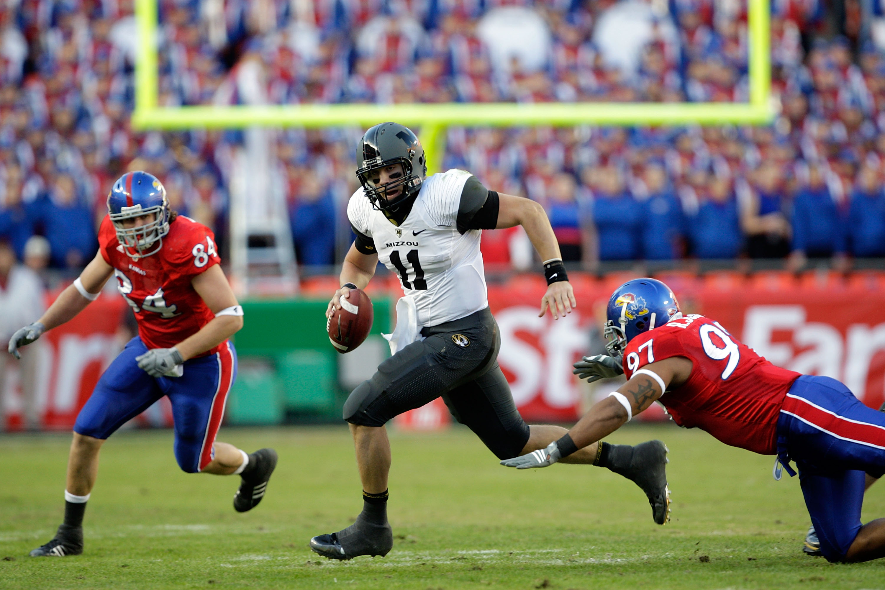 KANSAS CITY, MO - NOVEMBER 28: Quarterback Blaine Gabbert #11 of the Missouri Tigers scrambles as Jeff Wheeler #84 and Richard Johnson Jr. #97 of the Kansas Jayhawks defend during the game at Arrowhead Stadium on November 28, 2009 in Kansas City, Missour