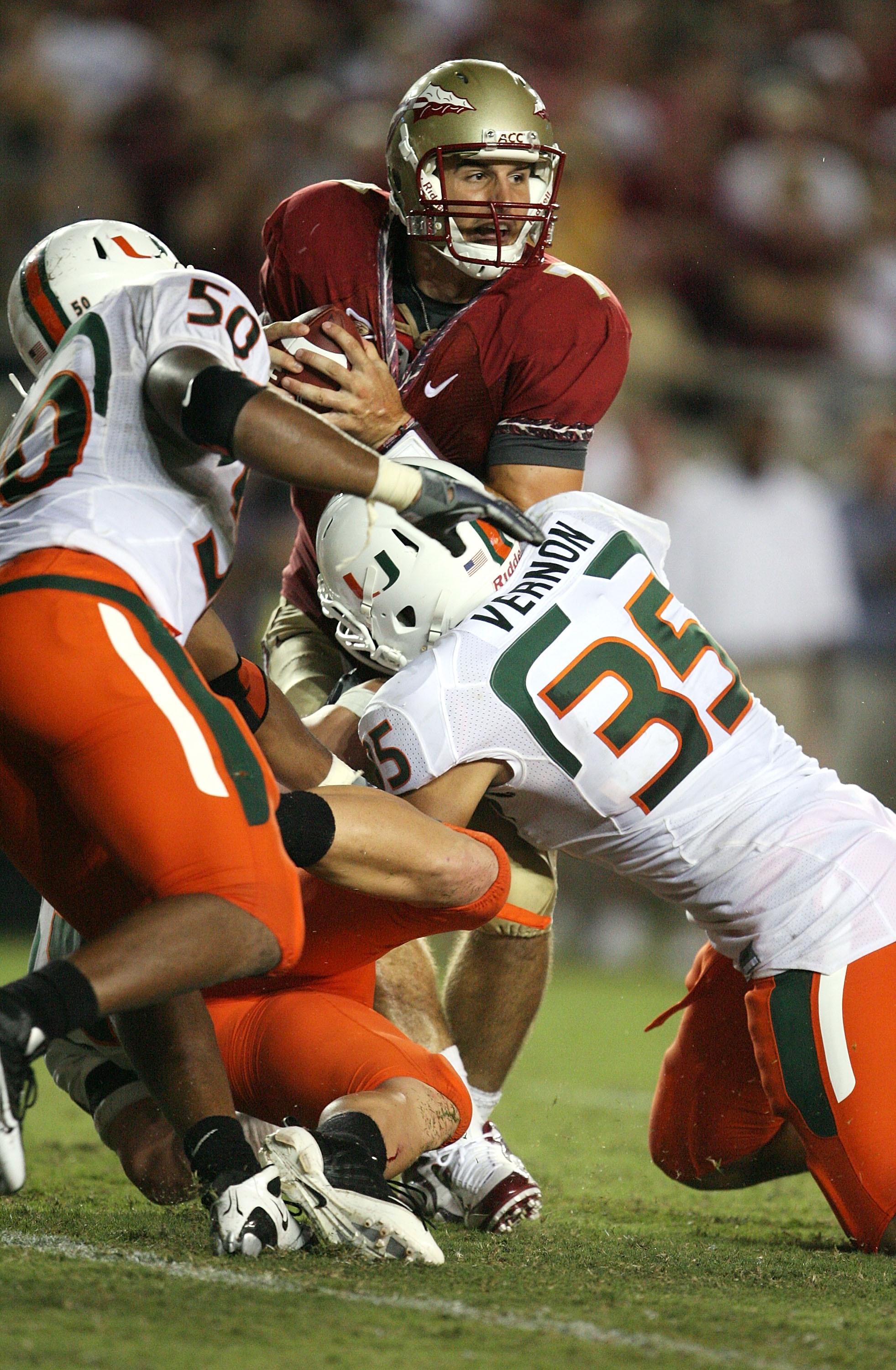 TALLAHASSEE, FL - SEPTEMBER 07:  Defenders Olivier Vernon #35, Colin McCarthy #44 and Darryl Sharpton #50 of the Miami Hurricanes bring down quarterback Christian Ponder #7 of the Florida State Seminoles during a goal line stand in the fourth quarter at D