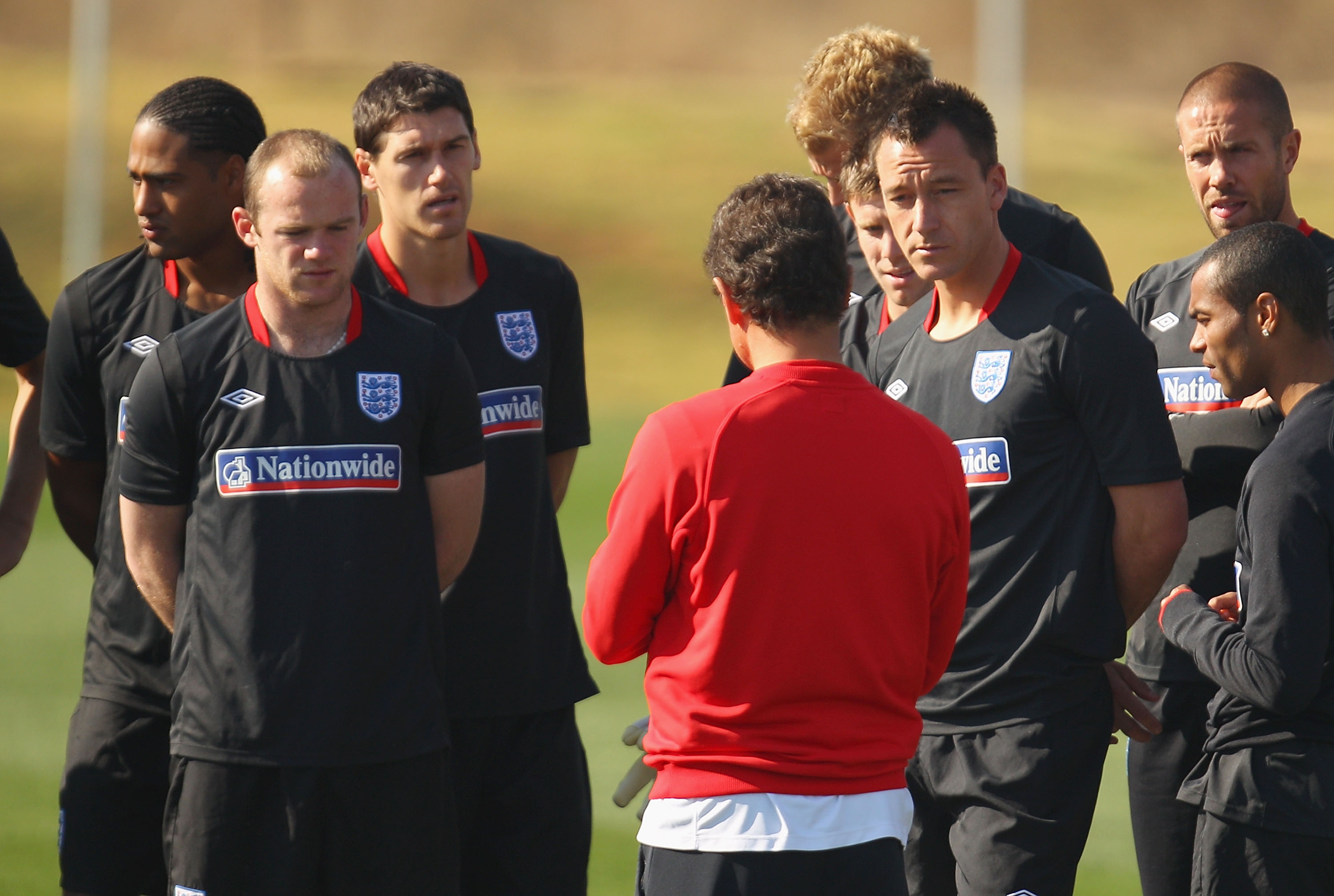 RUSTENBURG, SOUTH AFRICA - JUNE 24:  John Terry looks on as England coach Fabio Capello speaks to his team at an England training session during the FIFA 2010 World Cup at the Royal Bafokeng Sports Campus on June 24, 2010 in Rustenburg, South Africa.  (Ph
