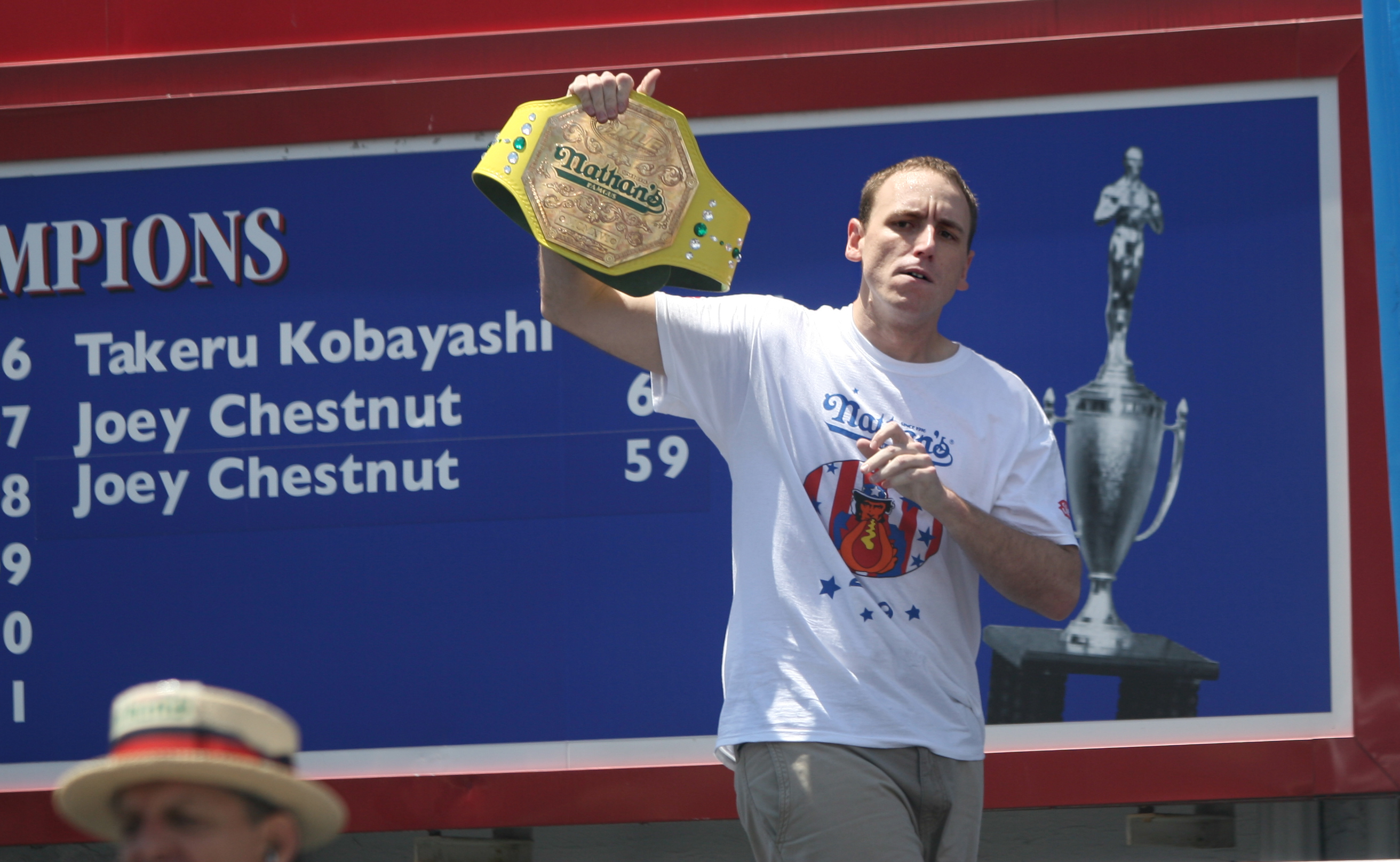 NEW YORK - JULY 4: Joey Chestnut of San Jose, California walks on stage holding his old champion belt as the Nathan's Famous Fourth of July hot dog eating contest begins on July 4, 2009 in Coney Island in the Brooklyn borough of New York City. Chestnut de