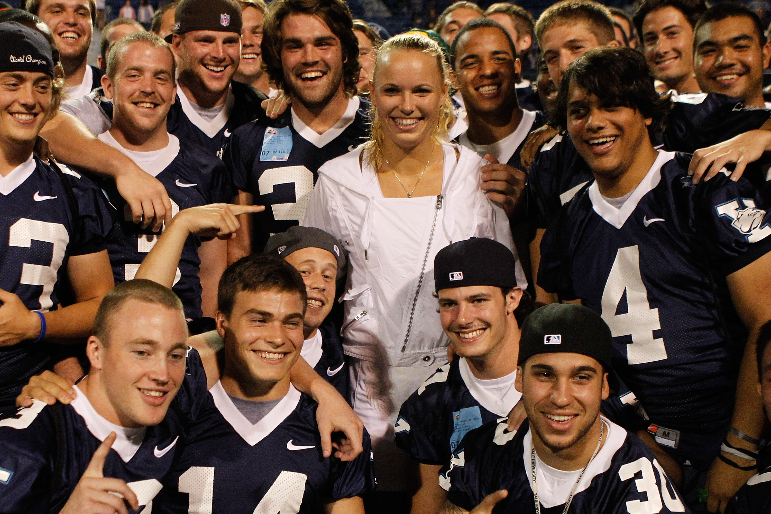 NEW HAVEN, CT - AUGUST 25:  Caroline Wozniacki of Denmark poses with members of the Yale football team in attendance for her match with Dominika Cibulkova of Slovakia during the Pilot Pen tennis tournament at the Connecticut Tennis Center on August 25, 20