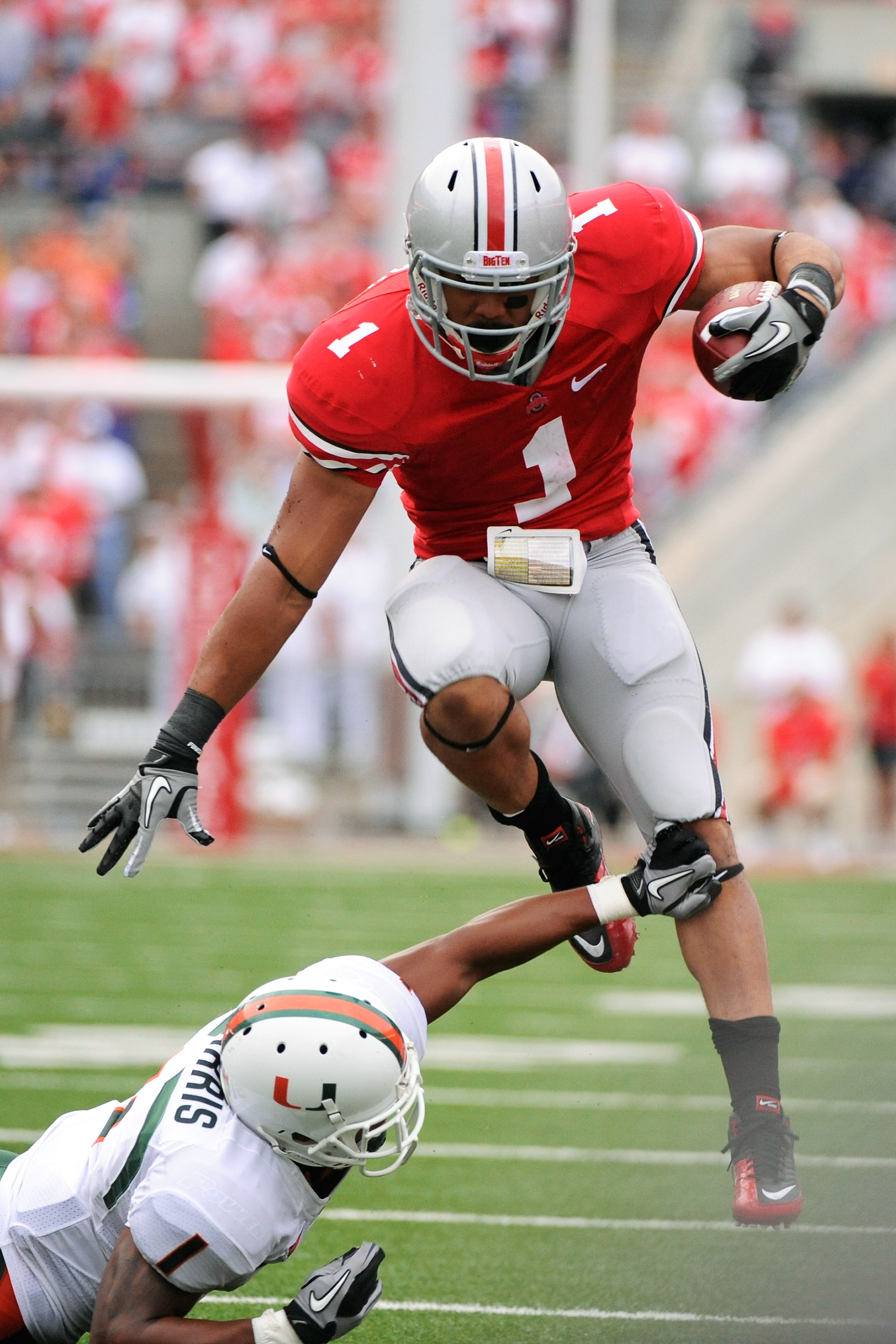 COLUMBUS, OH - SEPTEMBER 11: Dan Herron #1 of the Ohio State Buckeyes leaps over the tackle attempt of Brandon Harris #1 of the Miami Hurricanes at Ohio Stadium on September 11, 2010 in Columbus, Ohio. (Photo by Jamie Sabau/Getty Images)