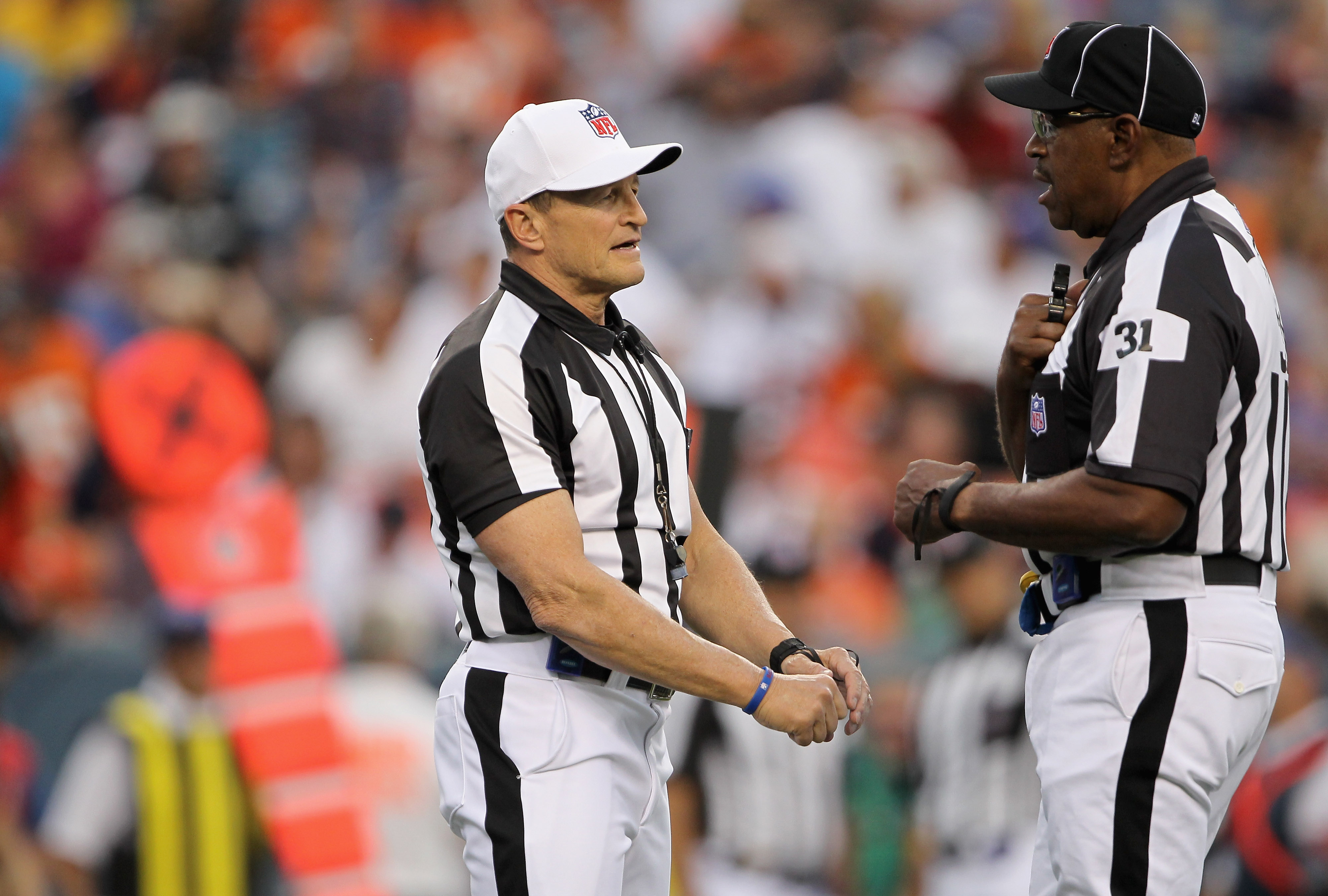 DENVER - AUGUST 21:  (L-R) Referee Ed Hochuli talks with umpire Chad Brown as they oversee the action between the Denver Broncos and the Detroit Lions during preseason NFL action at INVESCO Field at Mile High on August 21, 2010 in Denver, Colorado. The Li