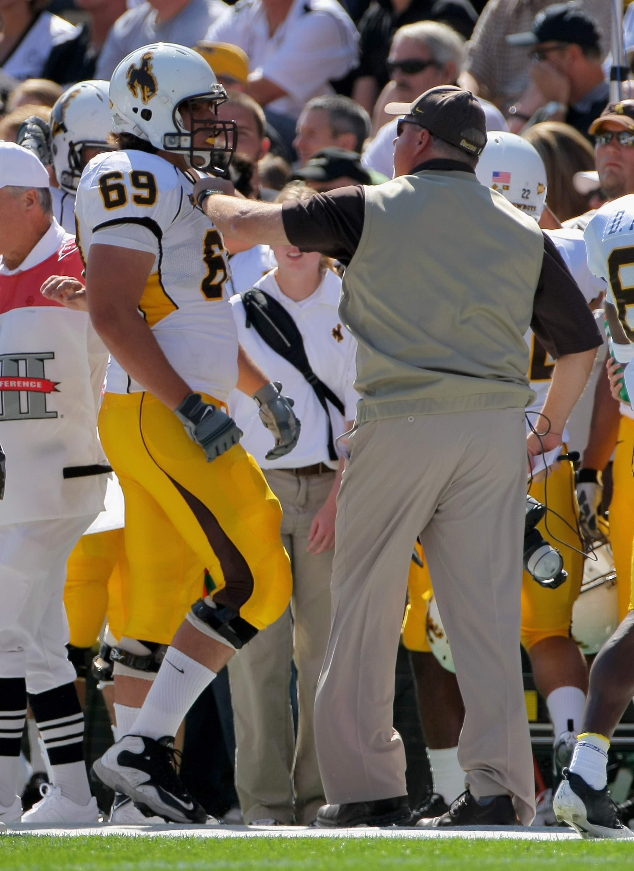 BOULDER, CO - SEPTEMBER 19: Head coach Dave Christensen of the Wyoming Cowboys grabs right tackle John Hutchins #69 as he comes off the field and has words for him after he was called for illegal motion against the Colorado Buffaloes at Folsom Field on S