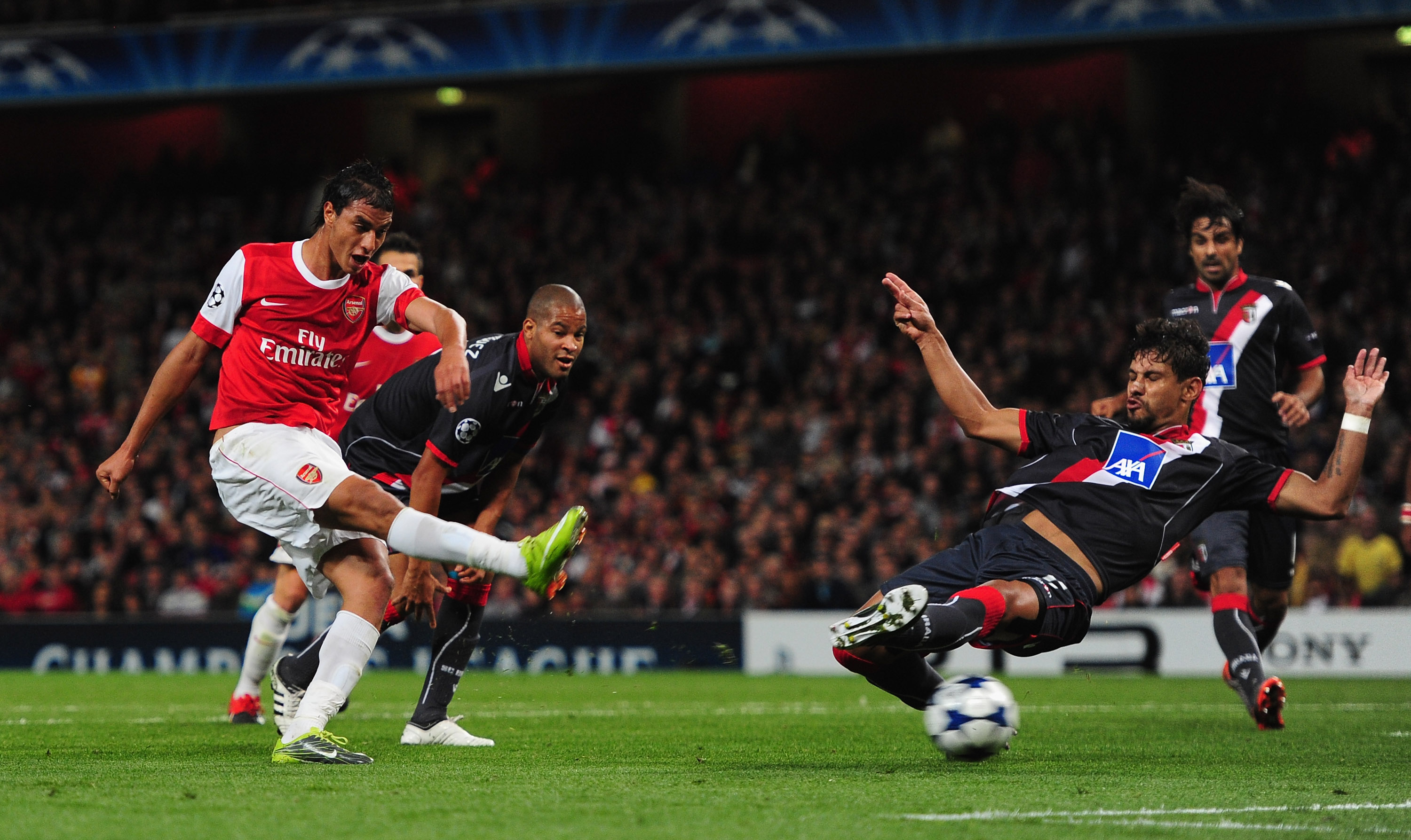 LONDON, ENGLAND - SEPTEMBER 15:  Marouane Chamakh of Arsenal scores his team's third goal despite the efforts of Moises of Braga during the UEFA Champions League Group H match between Arsenal and SC Braga at the Emirates Stadium on September 15, 2010 in L