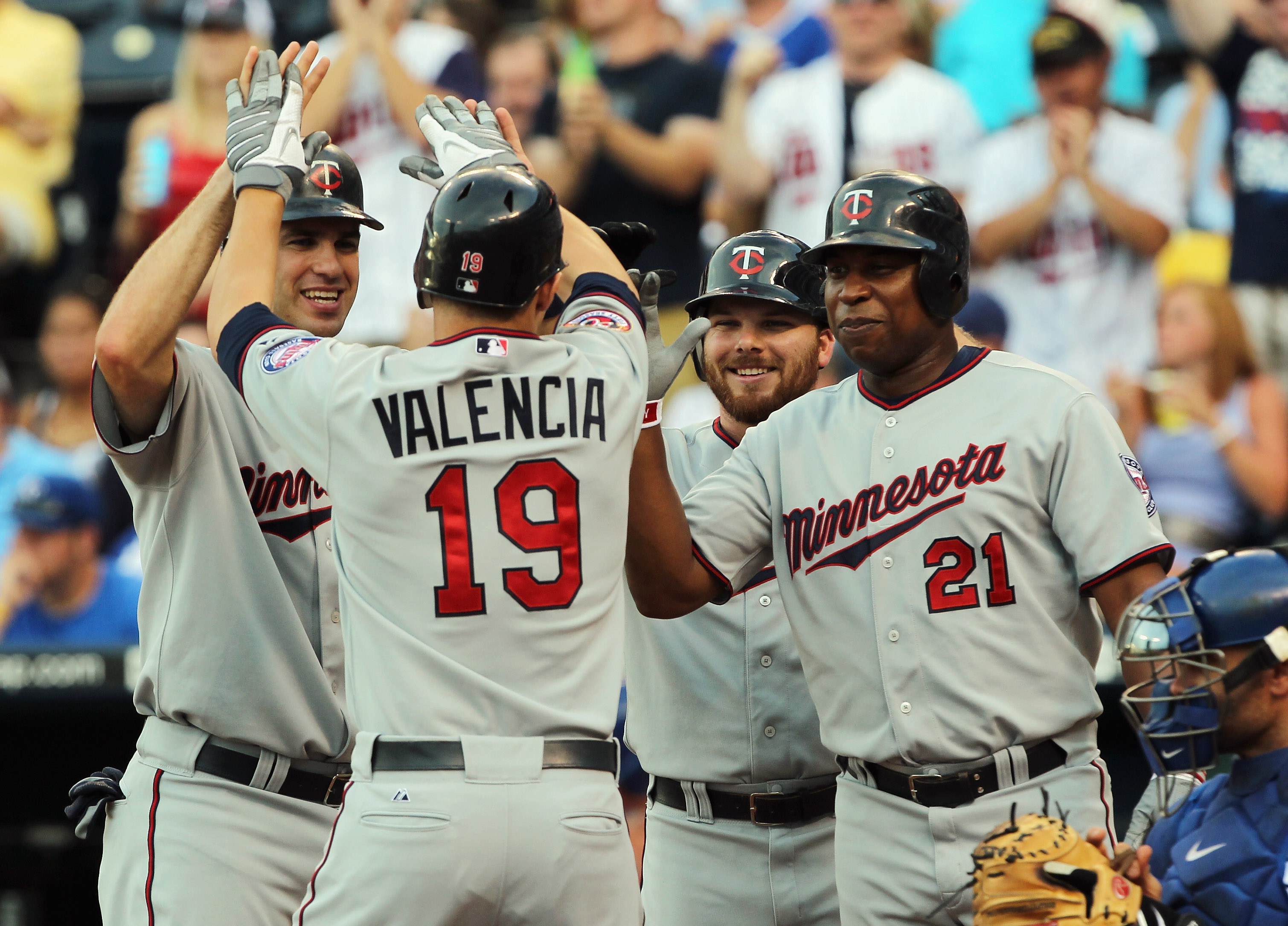 KANSAS CITY, MO - JULY 26:  Danny Valencia #19 of the Minnesota Twins is congratulated by teammates Joe Mauer #7, Jason Kubel #16 and Delmon Young #21 at home plate after hitting a grand slam home run during the 1st inning of the game against the Kansas C
