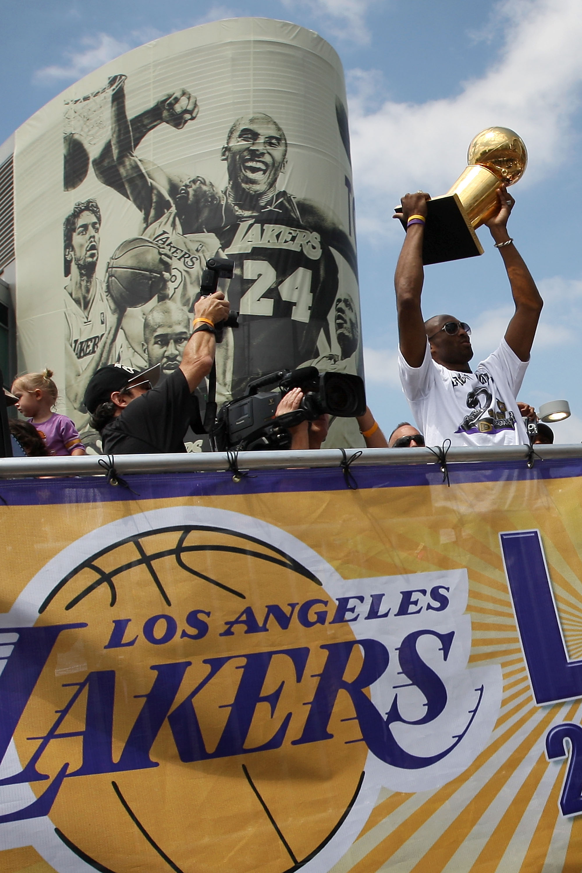 LOS ANGELES, CA - JUNE 21:  Los Angeles Lakers guard Kobe Bryant hoists the championship trophy as he rides past a mural featuring himself during the victory parade for the the NBA basketball champion team on June 21, 2010 in Los Angeles, California. The