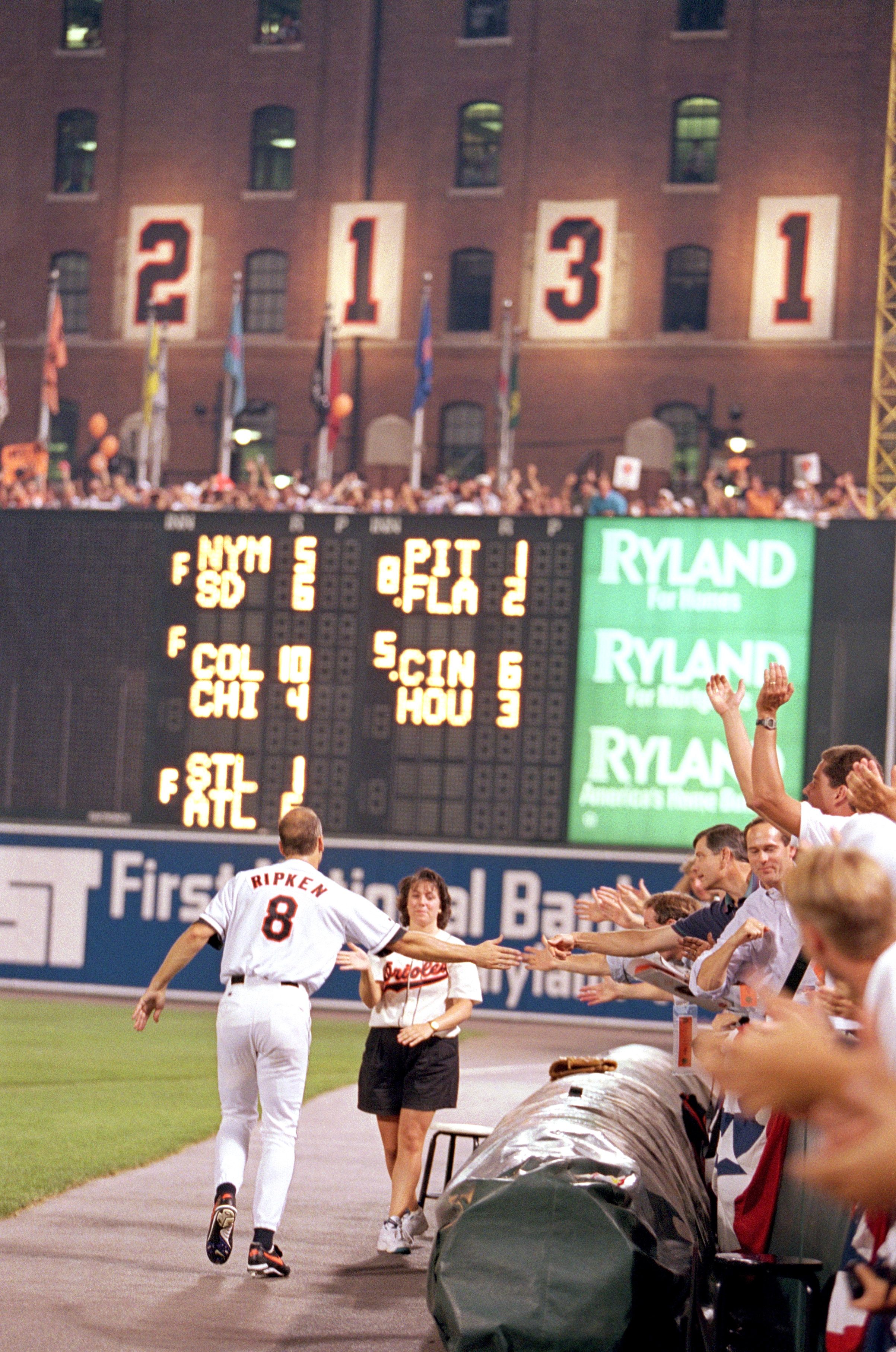 BALTIMORE - SEPTEMBER 6:  Cal Ripken Jr. #8 of the Baltimore Orioles high-fives fans along side the warning track as he celebrates breaking Lou Gehrig's record for consecutive game played with his 2131 career game, during a game against the California Ang