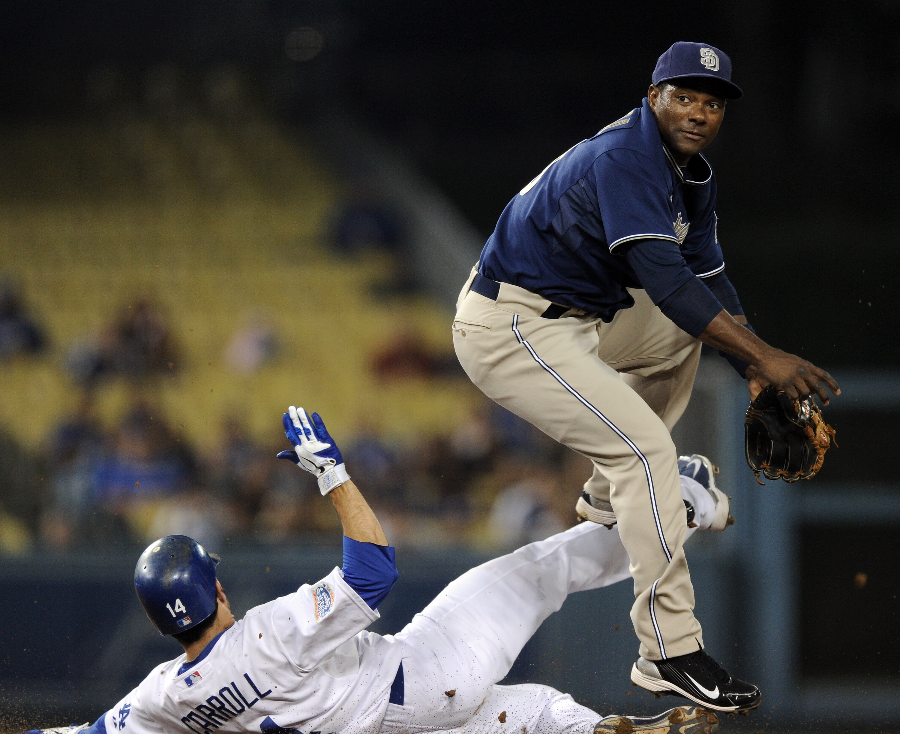 LOS ANGELES, CA - SEPTEMBER 21:  Miguel Tejada #10 of the San Diego Padres jumps away from the slide of Jamey Carroll #14 of the Los Angeles Dodgers to complete a double play during the first inning at Dodger Stadium on September 21, 2010 in Los Angeles,