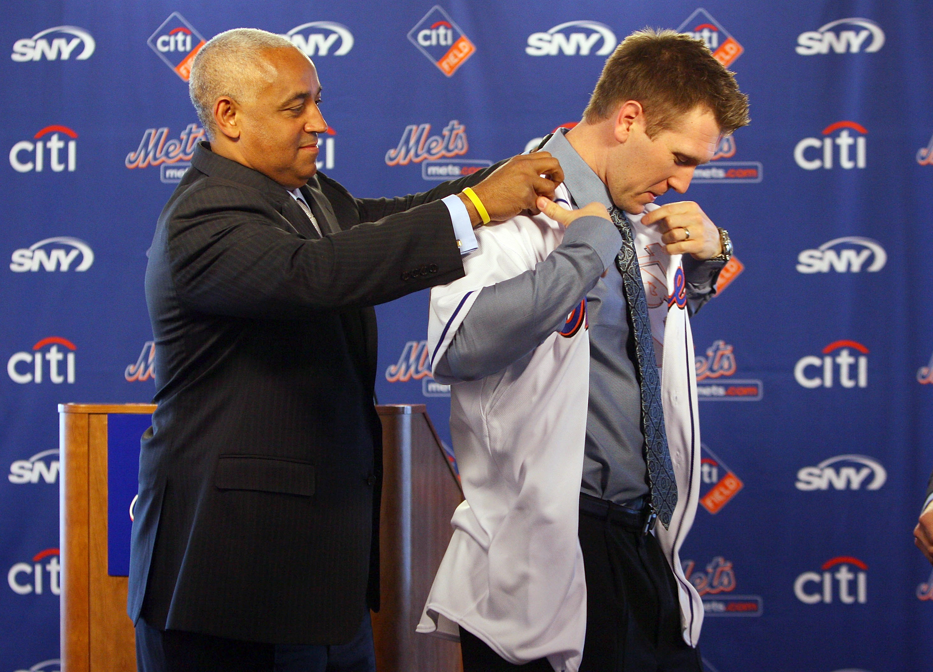 NEW YORK - JANUARY 05:  General manager Omar Minaya helps Jason Bay try on his jersey during a press conference to announce Bay's signing to the New York Mets on January 5, 2010 at Citi Field in the Flushing neighborhood of the Queens borough of New York