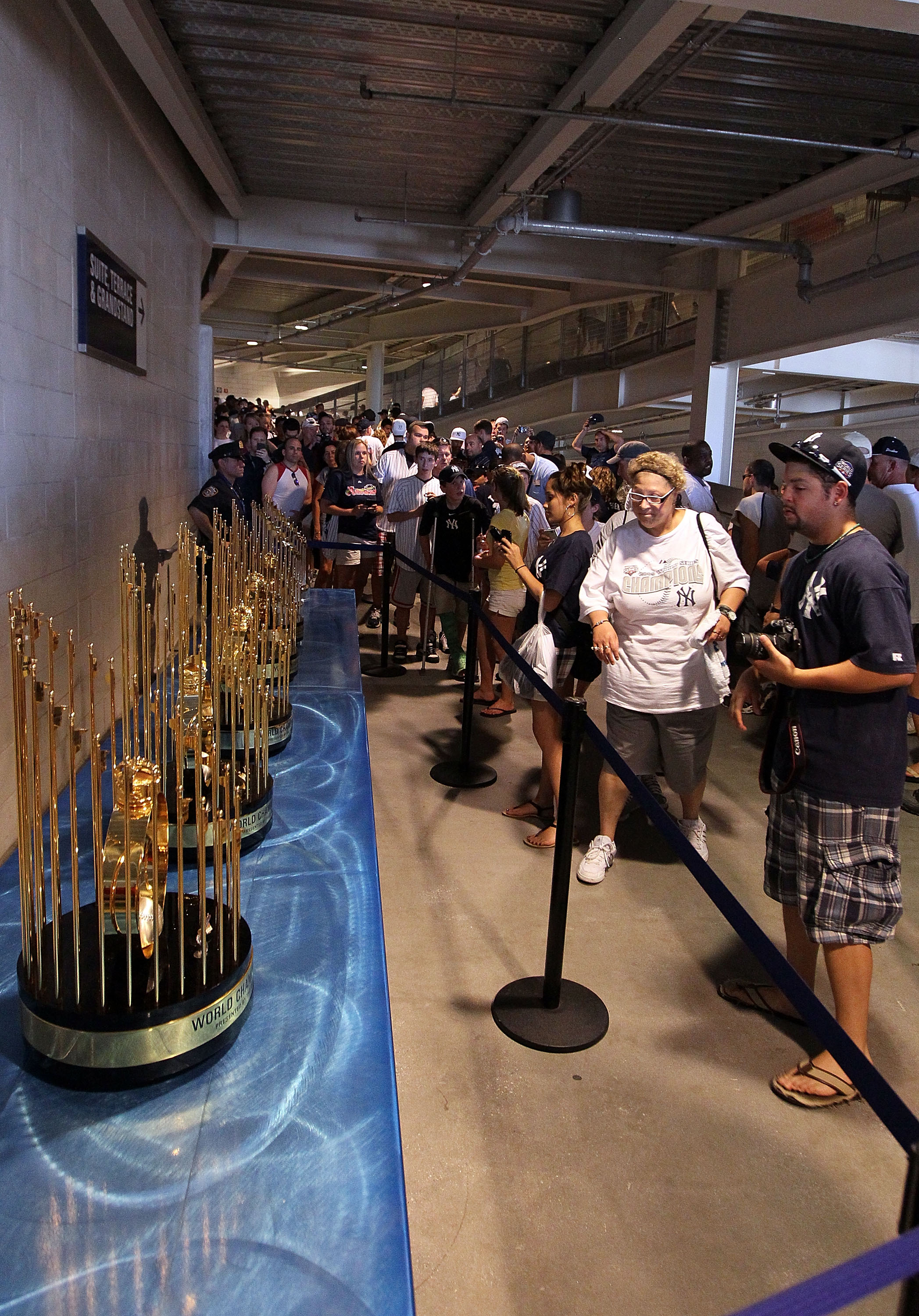 NEW YORK - JULY 04:  Fans photograph the seven World Series championship trophies won by the New York Yankees under the ownership of George Steinbrenner prior to the game against the Toronto Blue Jays on July 4, 2010 at Yankee Stadium in the Bronx borough