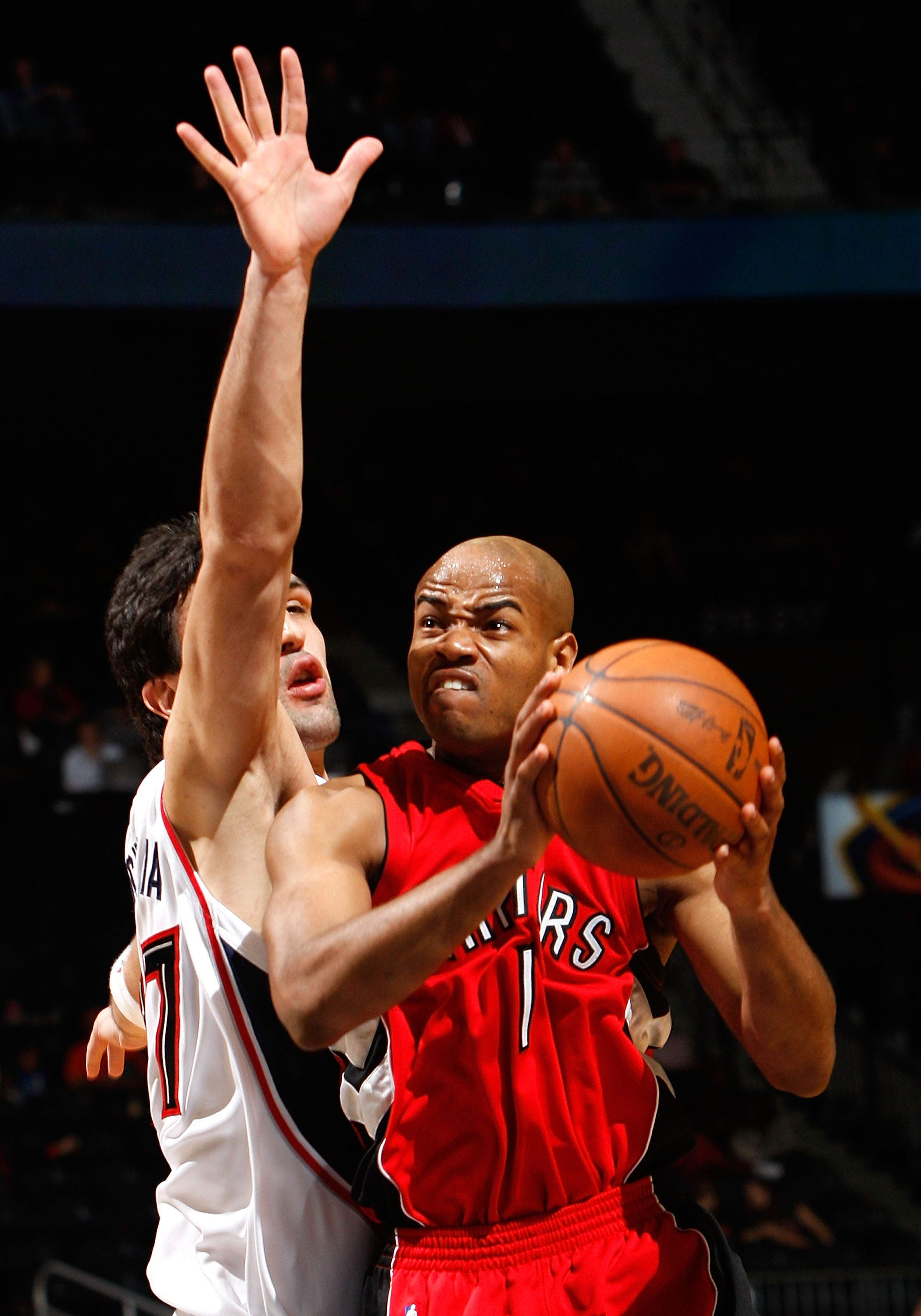 ATLANTA - DECEMBER 02:  Jarrett Jack #1 of the Toronto Raptors drives against Zaza Pachulia #27 of the Atlanta Hawks at Philips Arena on December 2, 2009 in Atlanta, Georgia.  NOTE TO USER: User expressly acknowledges and agrees that, by downloading and/o