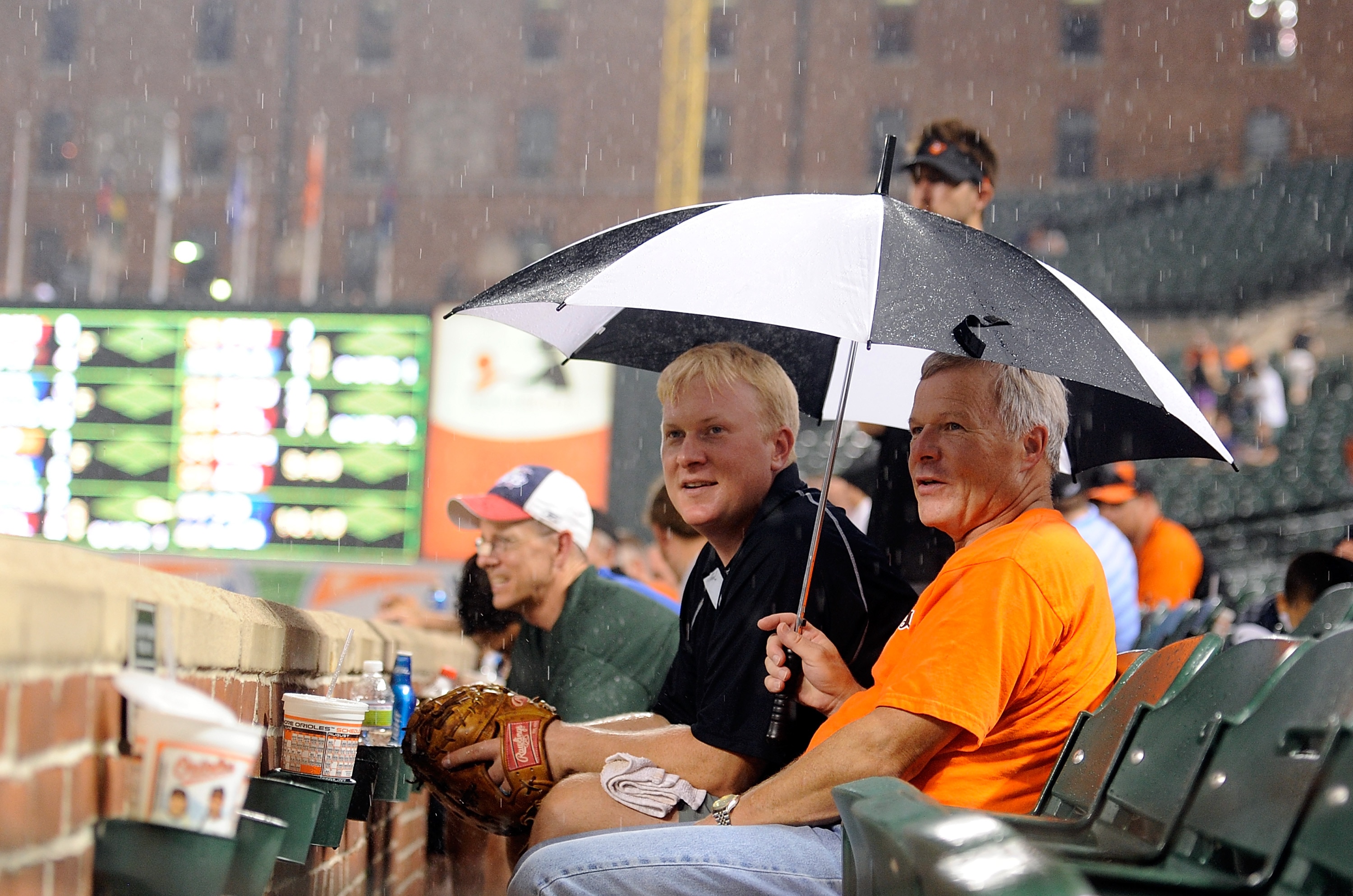 BALTIMORE - AUGUST 04: Fans watch the grounds crew put the tarp on the field during a rain delay in the sixth inning of the game between the Los Angeles Angels of Anaheim and the Baltimore Orioles at Camden Yards on August 4, 2010 in Baltimore, Maryland.