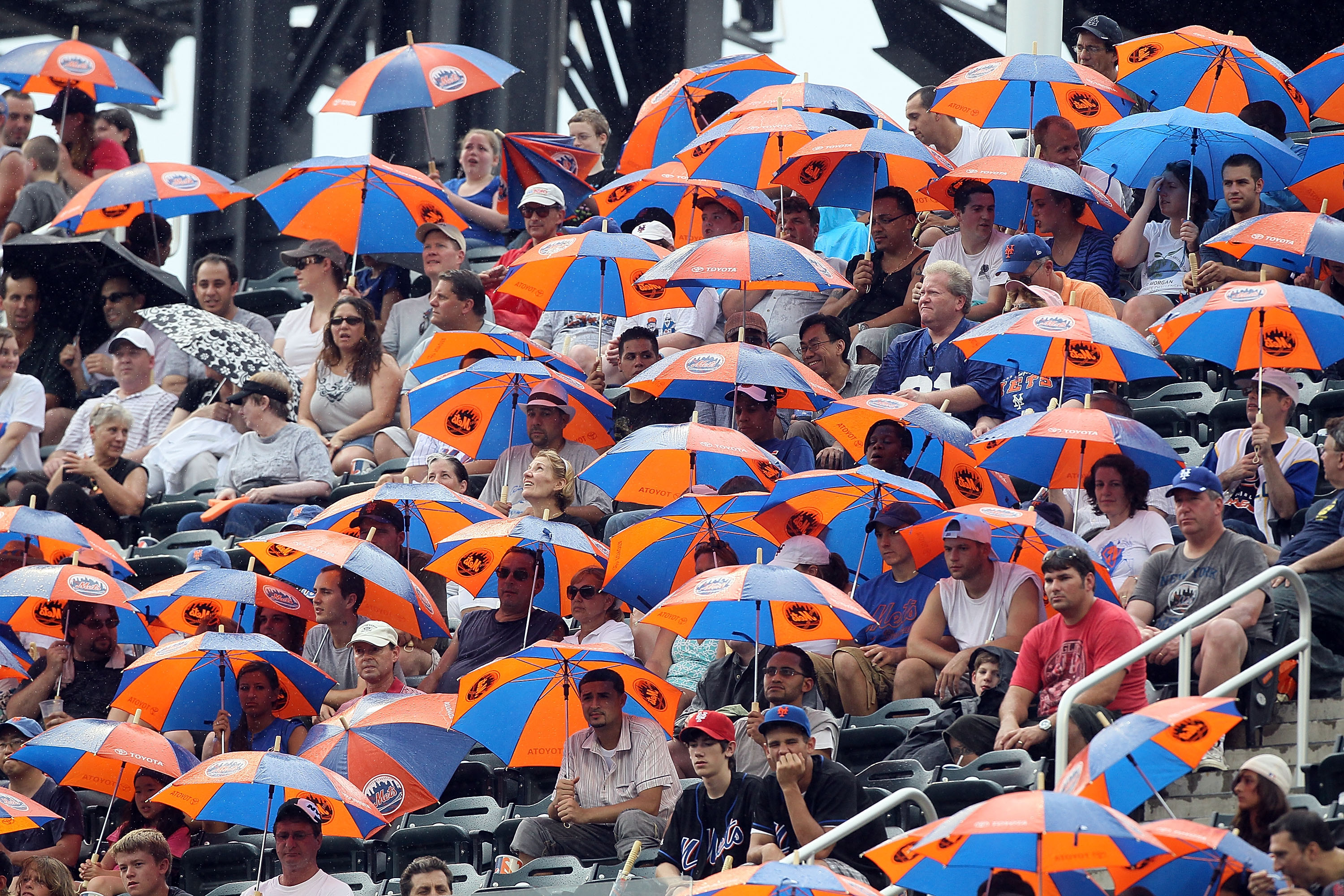 NEW YORK - JULY 29:  Fans break out promotional umbrellas as rain starts to fall as the New York Mets play against the St. Louis Cardinals on July 29, 2010 at Citi Field in the Flushing neighborhood of the Queens borough of New York City. The Mets defeate