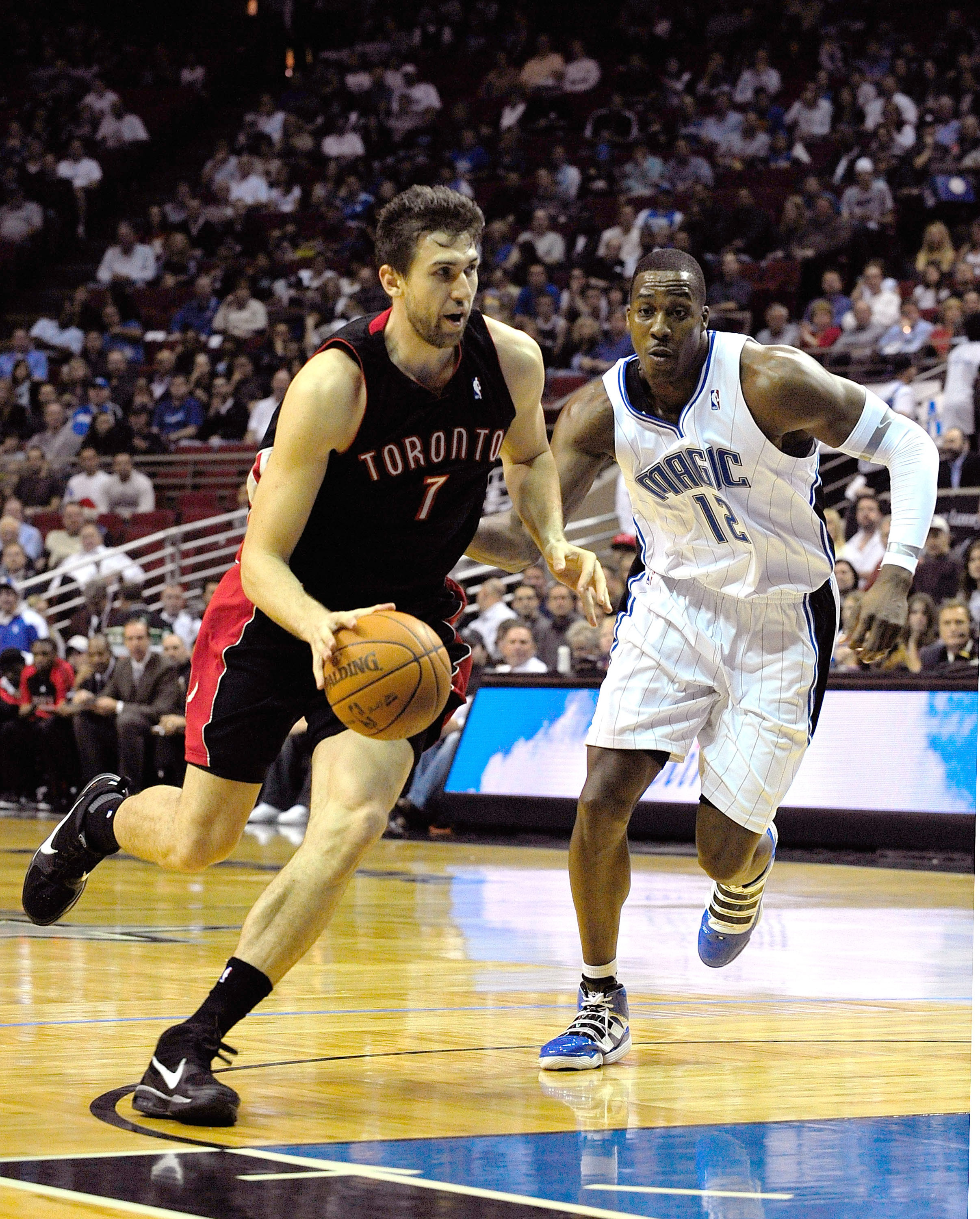 ORLANDO, FL - DECEMBER 16:  Andrea Bargnani #7 of the Toronto Raptors drives past Dwight Howard #12 of the Orlando Magic during the game at Amway Arena on December 16, 2009 in Orlando, Florida.  NOTE TO USER: User expressly acknowledges and agrees that, b