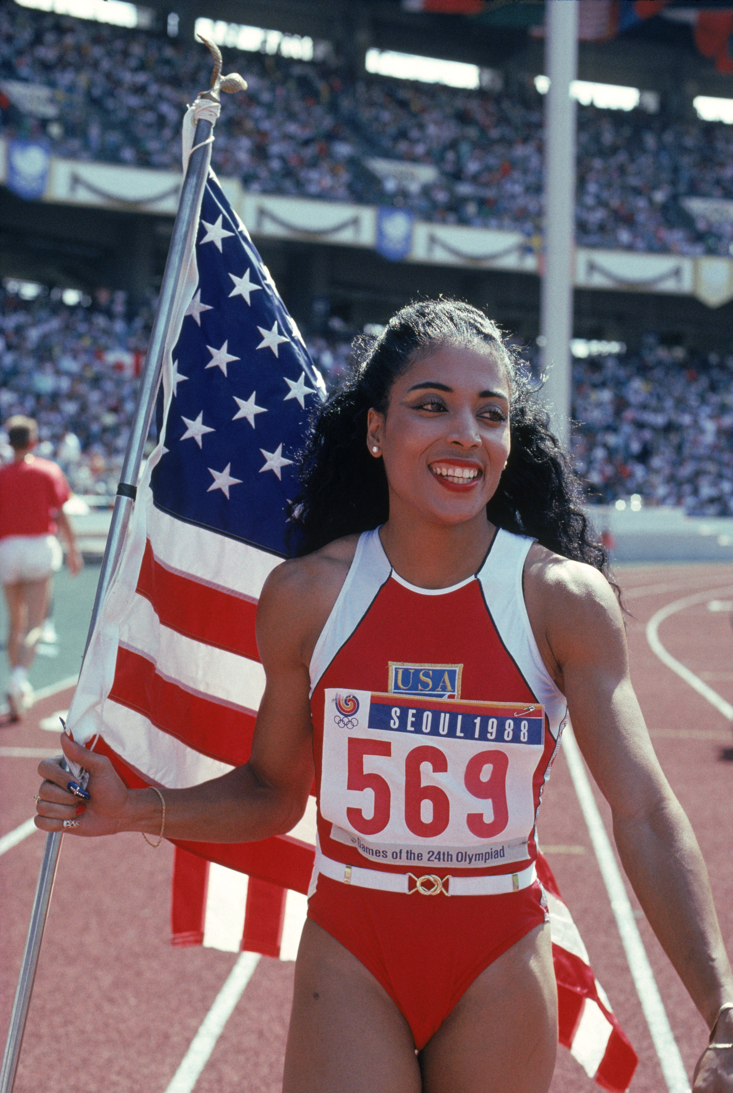 SEOUL, SOUTH KOREA - SEPTEMBER 28:  Florence Griffith Joyner of the USA walks with the American Flag as she celebrates setting a new Olympic record to win the gold medal in the Women's 100 meters dash final during the 1988 Summer Olympic Games on Septembe