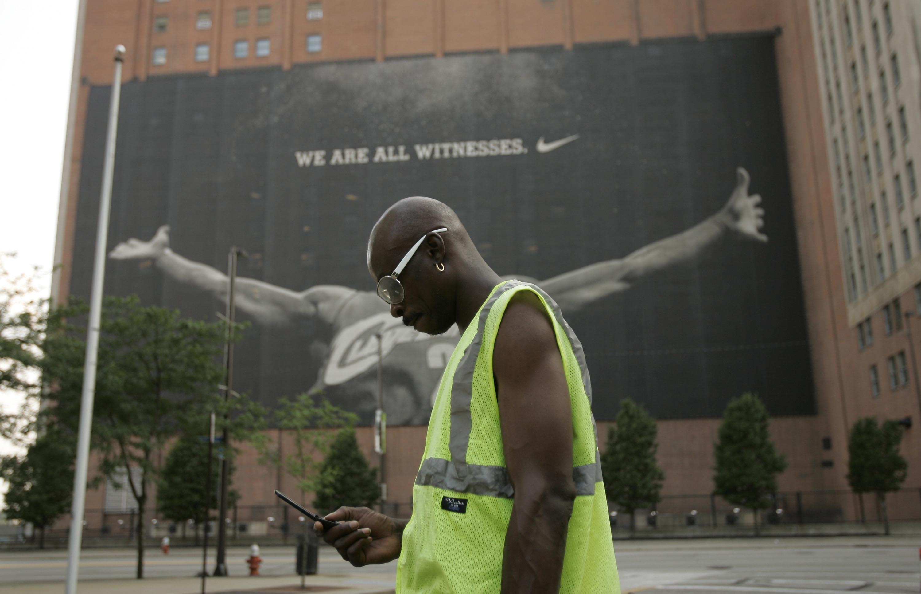 CLEVELAND - JULY 8:  A parking attendant stands near a larger than life photograph of LeBron James July 8, 2010 in Cleveland, Ohio. The two-time Most Valuable Player has the choice of remaining with the Cleveland Cavaliers or signing with a new team. (Pho