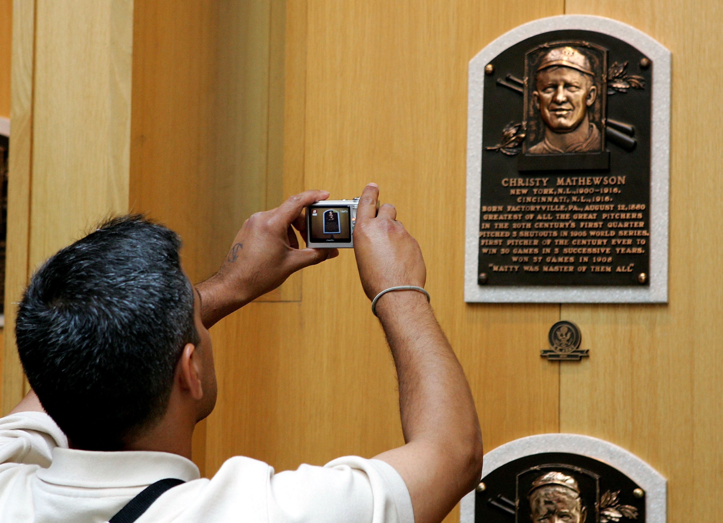 COOPERSTOWN, NY - JULY 29:  A baseball fan photograghs the plaque of Christy Mathewson at the National Baseball Hall of Fame and Museum during the Baseball Hall of Fame weekend on July 29, 2006 in Cooperstown, New York.  (Photo by Jim McIsaac/Getty Images