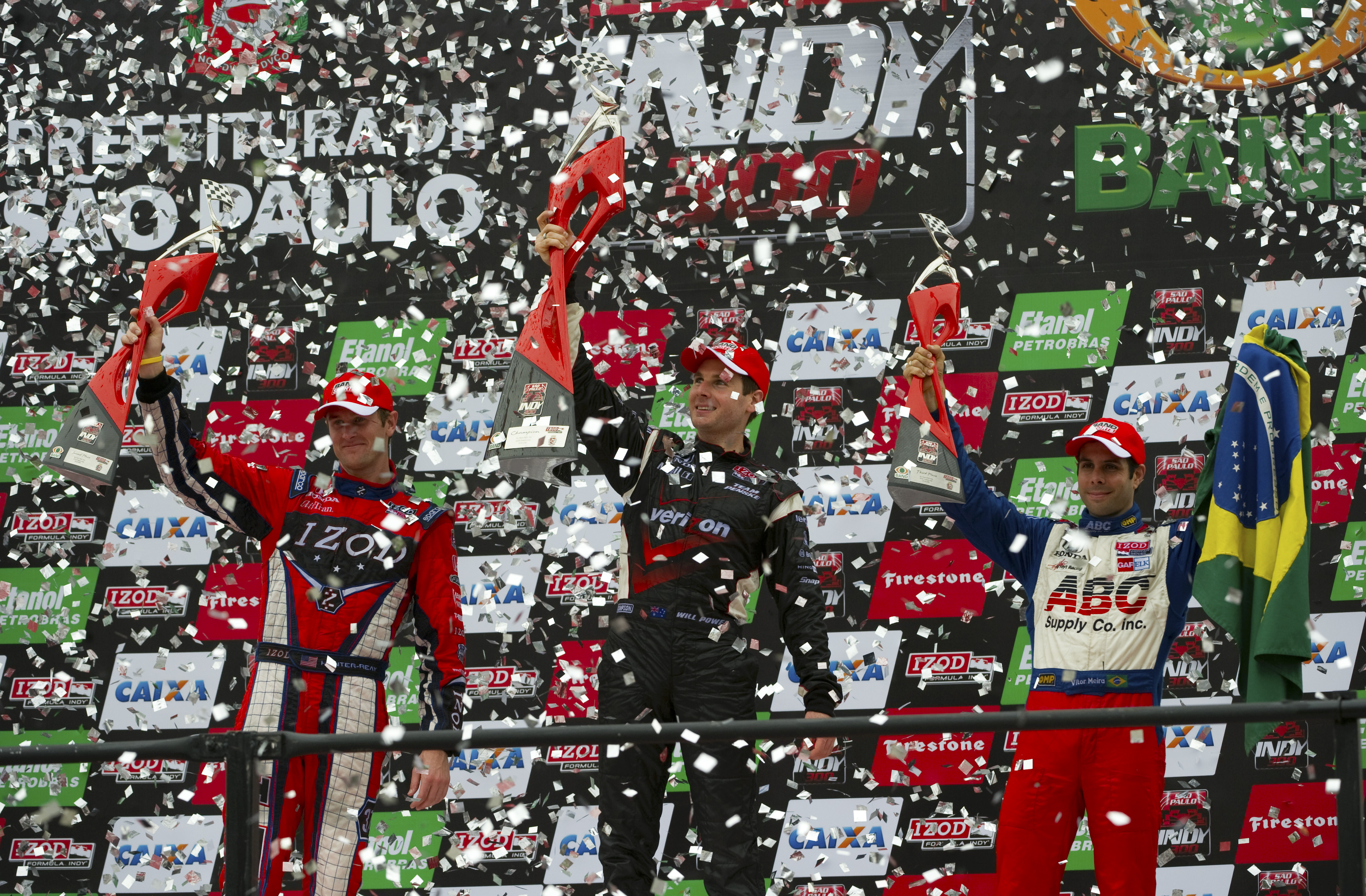SAO PAULO, BRAZIL - MARCH 14: Will Power (center) driver of the #12 Verizon Team Penske Dallara Honda lifts the winner's trophy on the podium after winning the IZOD IndyCar Series Sao Paulo Indy 300 as Ryan Hunter-Reay (left) in second place and Vitor Me