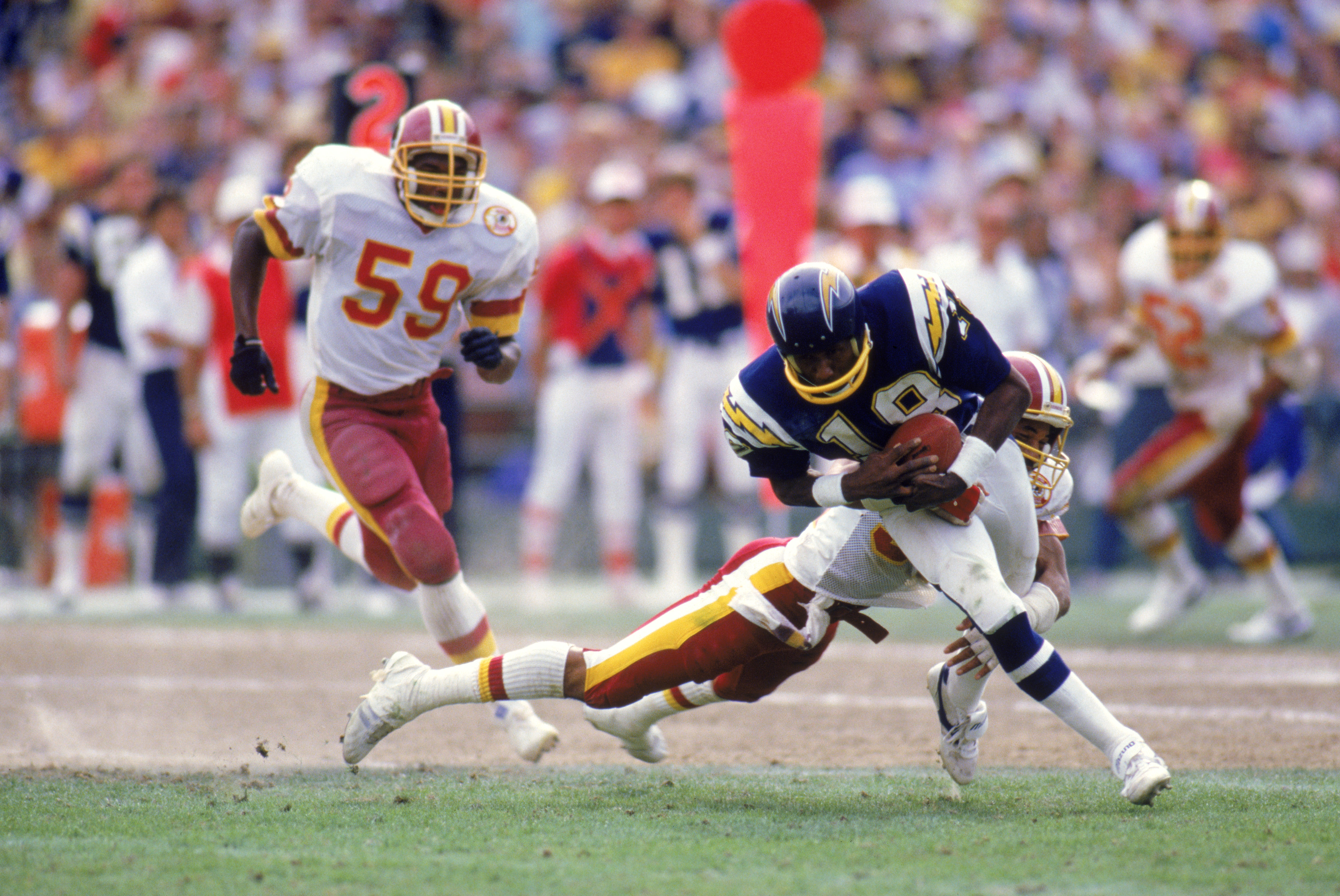 SAN DIEGO - 1985:  Wide receiver Charlie Joiner #18 of the San Diego Chargers runs with the ball as he is being tackled from behind during a game against the Washington Redskins in 1985 at Jack Murphy Stadium in San Diego, California.  (Photo by Rick Stew