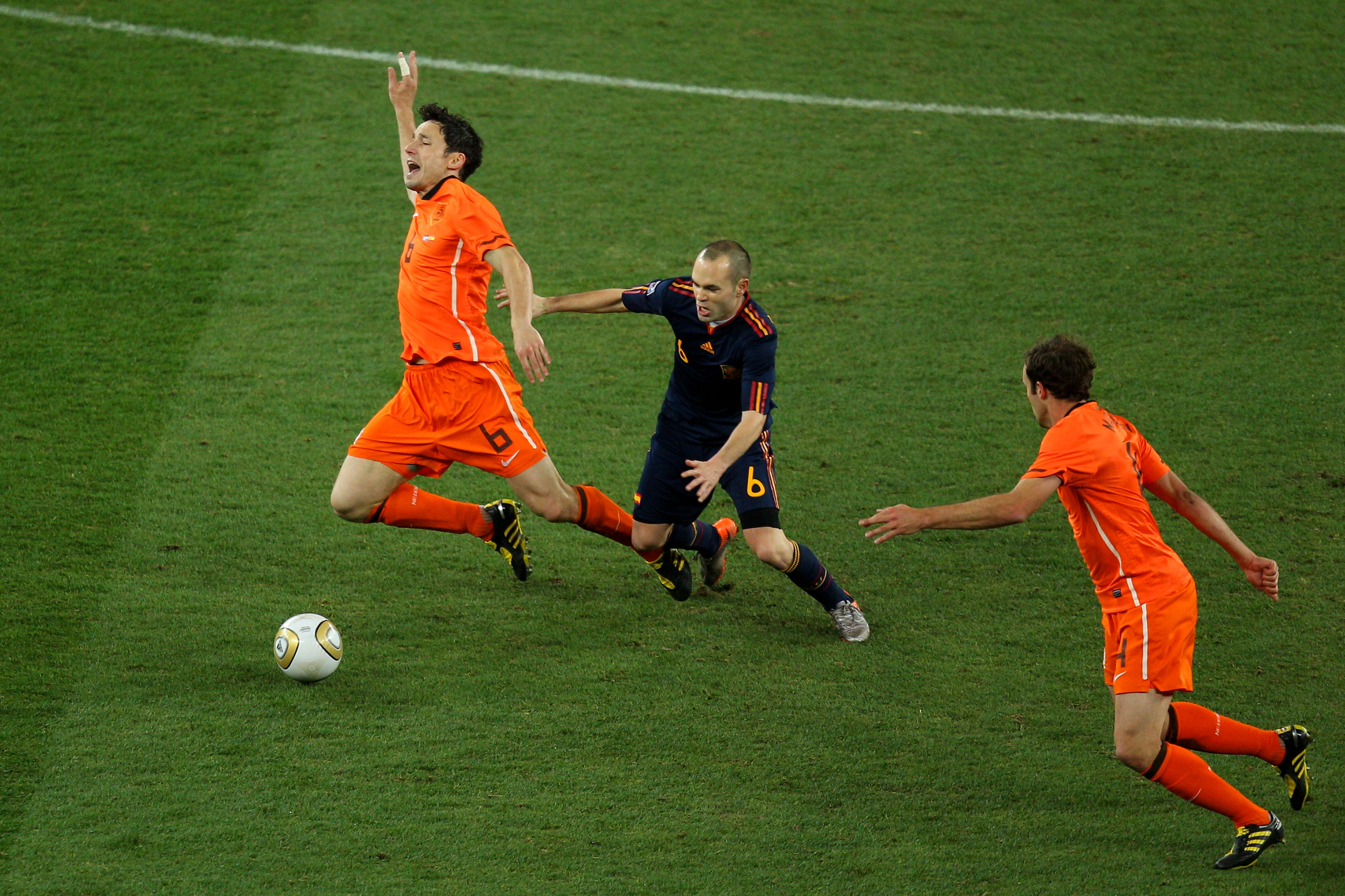 JOHANNESBURG, SOUTH AFRICA - JULY 11:  Mark Van Bommel of the Netherlands falls under the challenge of Andres Iniesta of Spain during the 2010 FIFA World Cup South Africa Final match between Netherlands and Spain at Soccer City Stadium on July 11, 2010 in