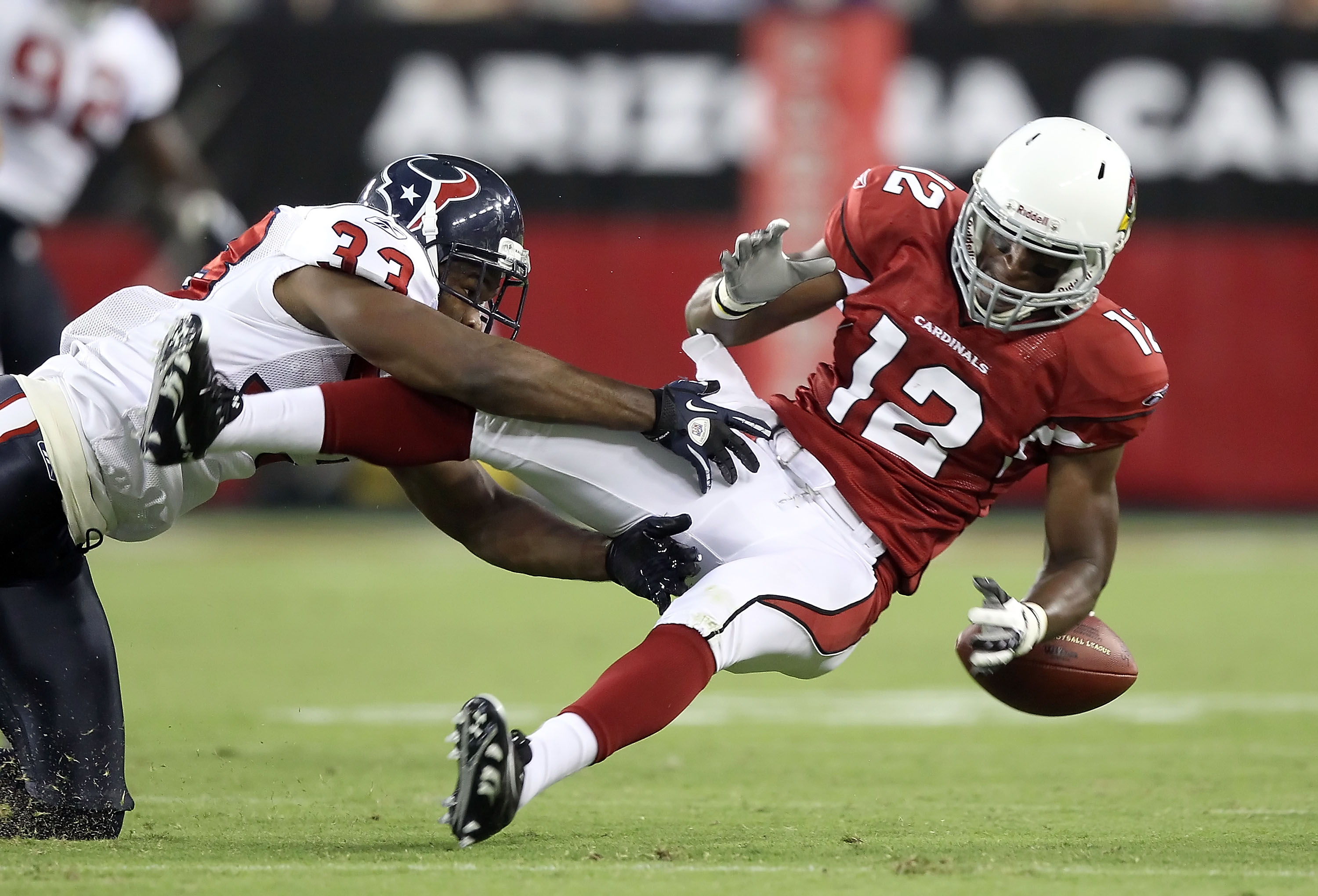 GLENDALE, AZ - AUGUST 14:  Wide receiver Andre Roberts #12 of the Arizona Cardinals loses the ball as he is hit by Troy Nolan #33 of the Houston Texans during preseason NFL game at the University of Phoenix Stadium on August 14, 2010 in Glendale, Arizona.