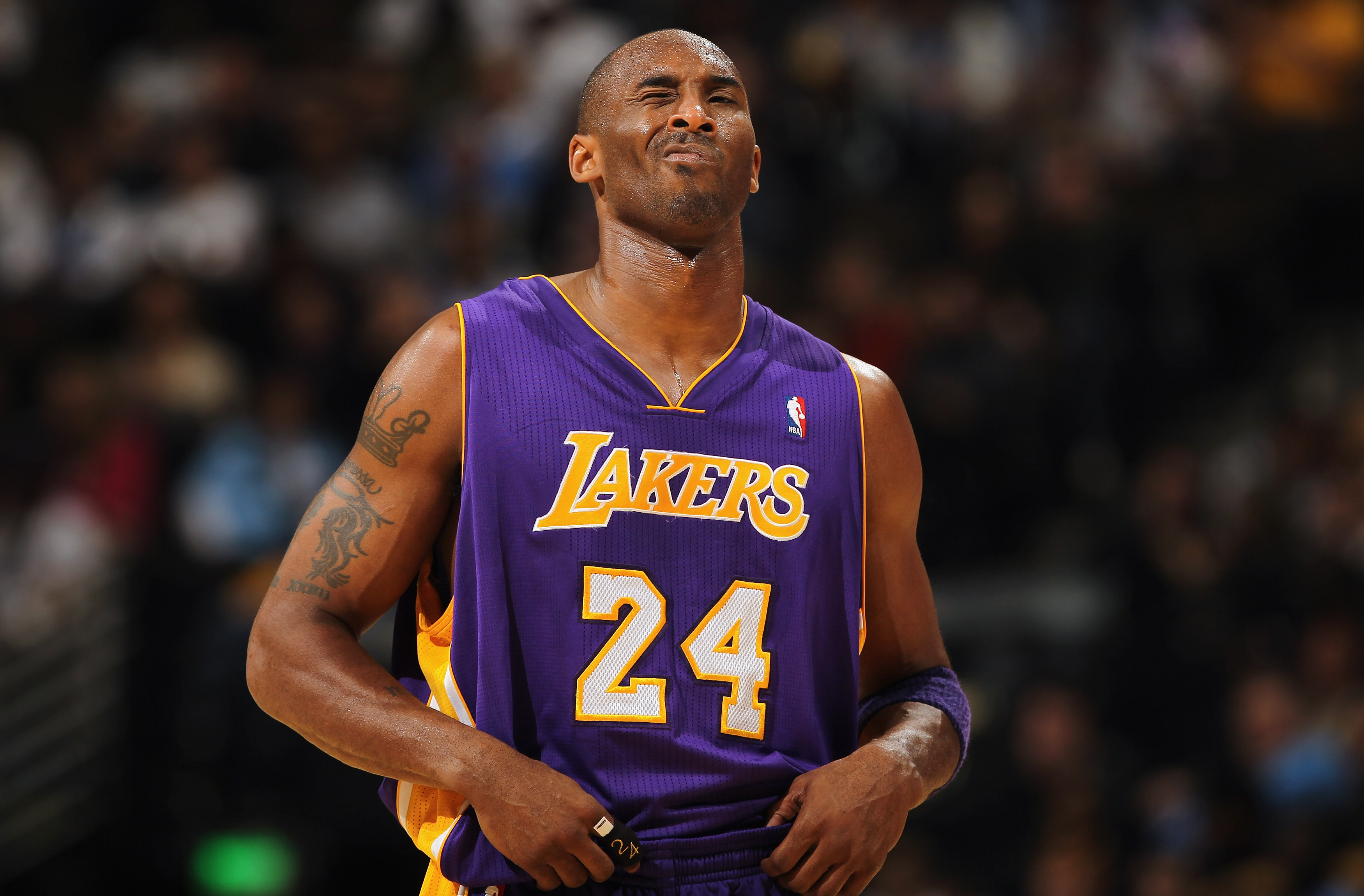 Kobe Bryant smiles and poses with a basketball wearing Laker home color  shoes and jersey at