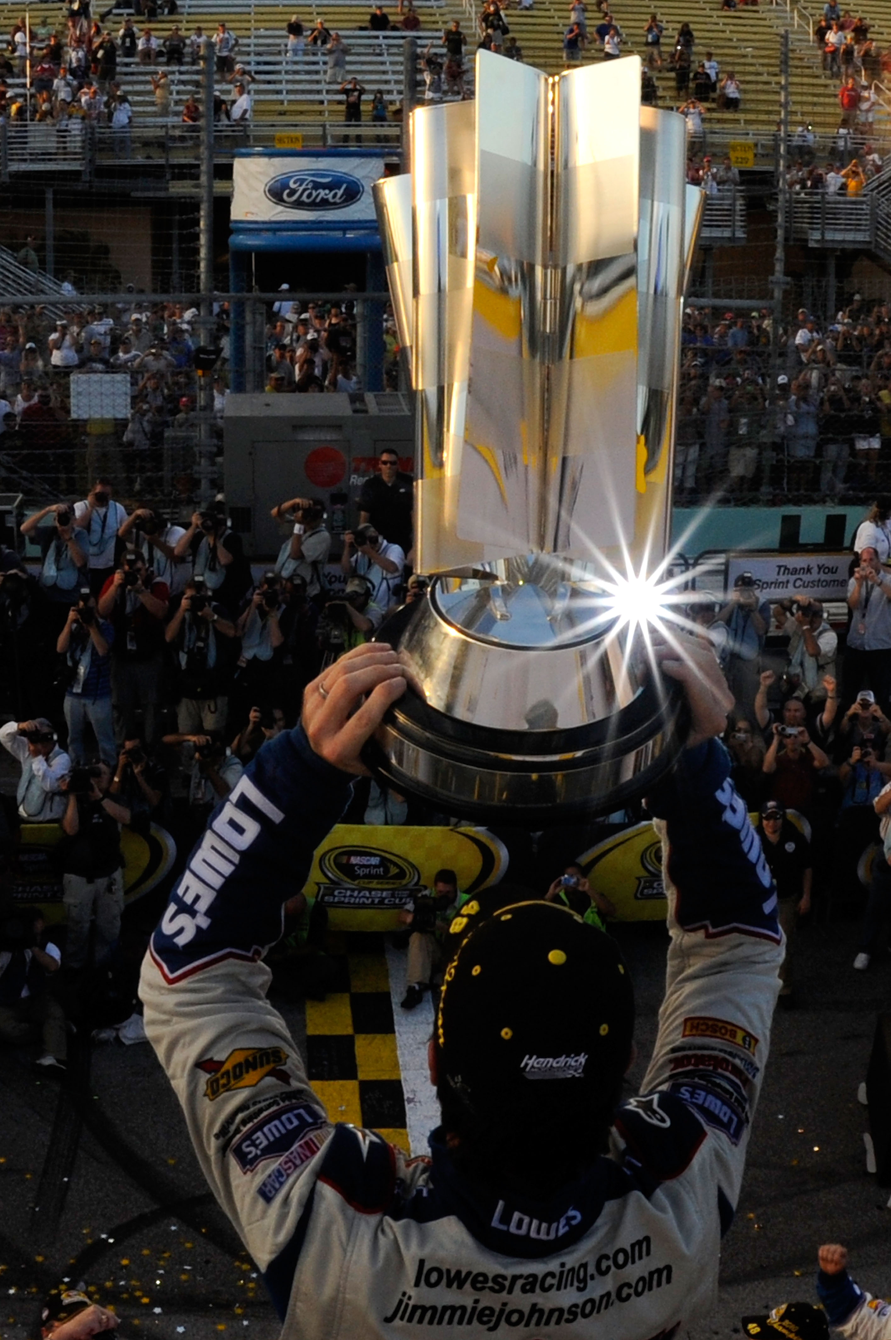 HOMESTEAD, FL - NOVEMBER 21:  Jimmie Johnson, driver of the #48 Lowe's Chevrolet, celebrates by hoisting the trophy after finishing in second place in the Ford 400 to clinch his fifth consecutive NASCAR Sprint Cup championship at Homestead-Miami Speedway 