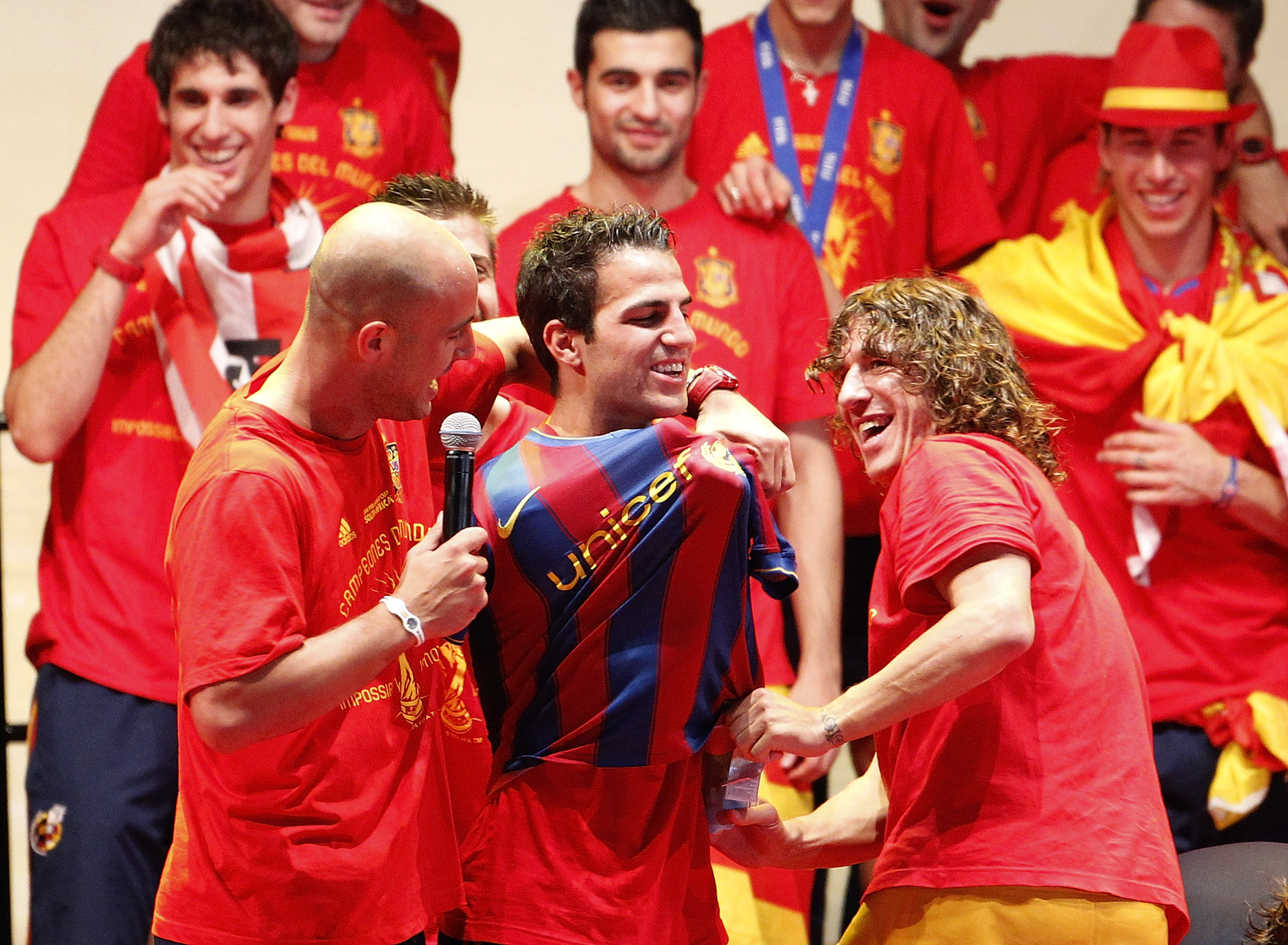 MADRID, SPAIN - JULY 12:  Pepe Reina (L) and Carles Puyol (R) of the Spanish national football team put a FC Barcelona shirt on Cesc Fabregas during the Spanish team's parade following their victory in the 2010 FIFA World Cup on July 12, 2010 in Madrid, S