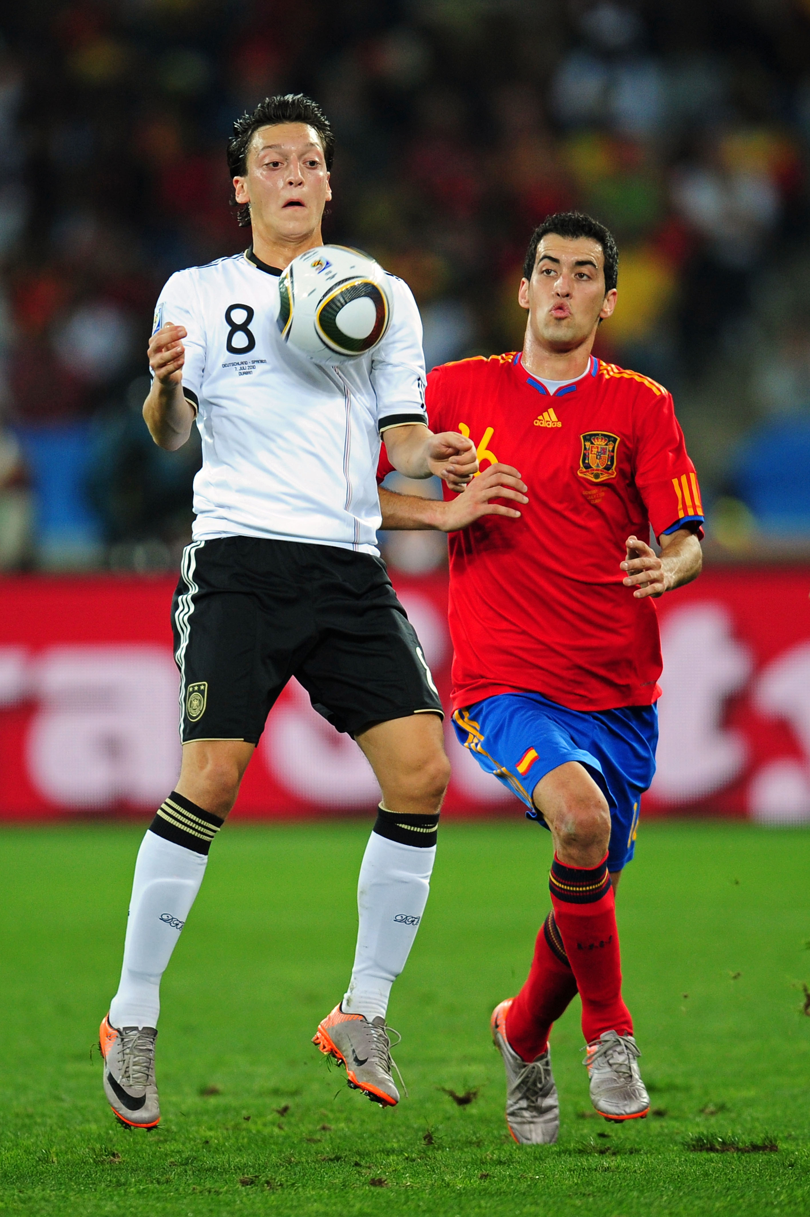 DURBAN, SOUTH AFRICA - JULY 07:  Mesut Oezil of Germany controls the ball on his chest as he is closed down by Sergio Busquets of Spain during the 2010 FIFA World Cup South Africa Semi Final match between Germany and Spain at Durban Stadium on July 7, 201
